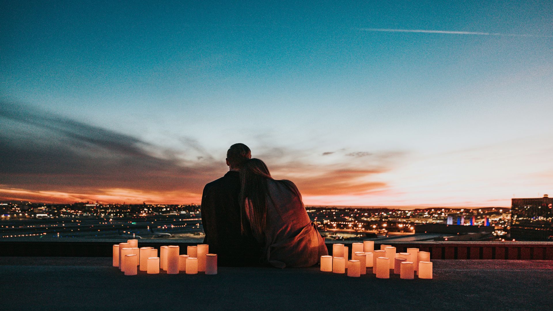 couple sitting on the field facing the city