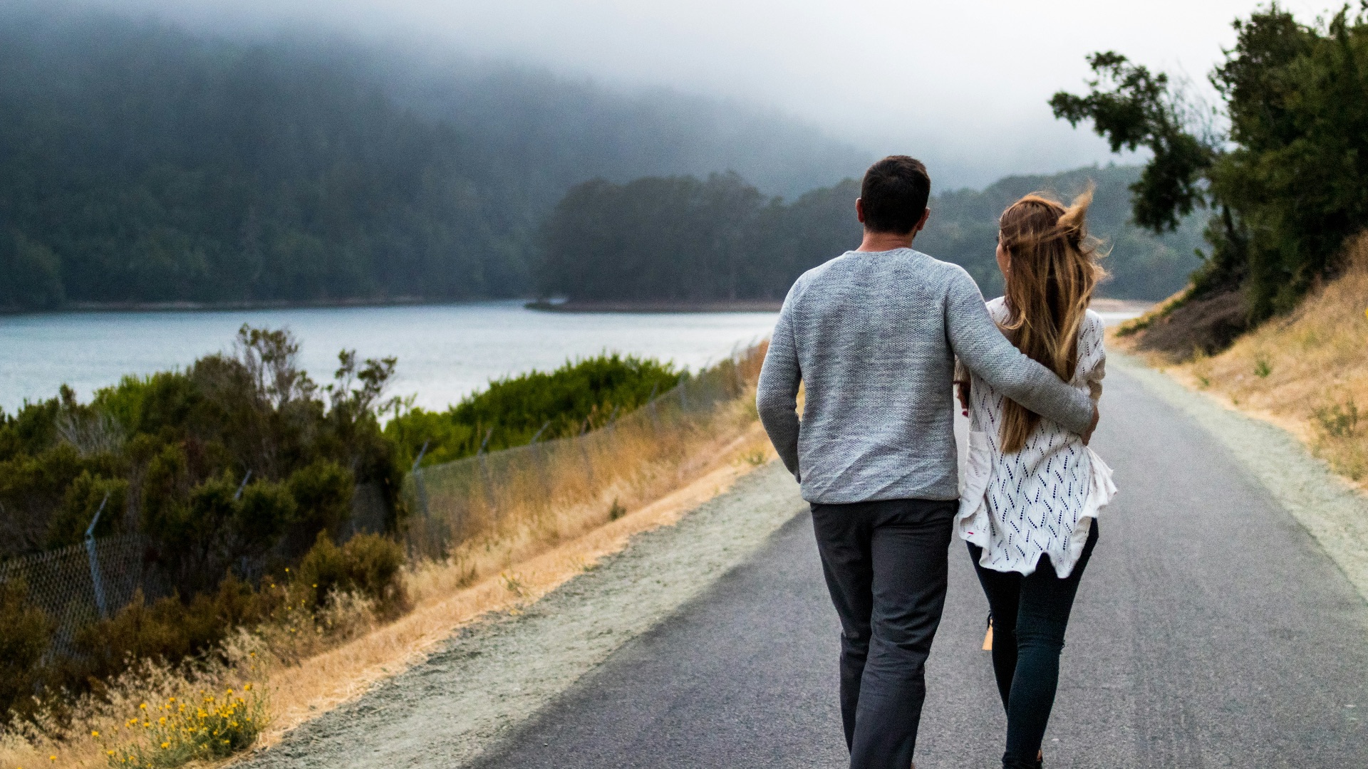 man and woman walking on asphalt road