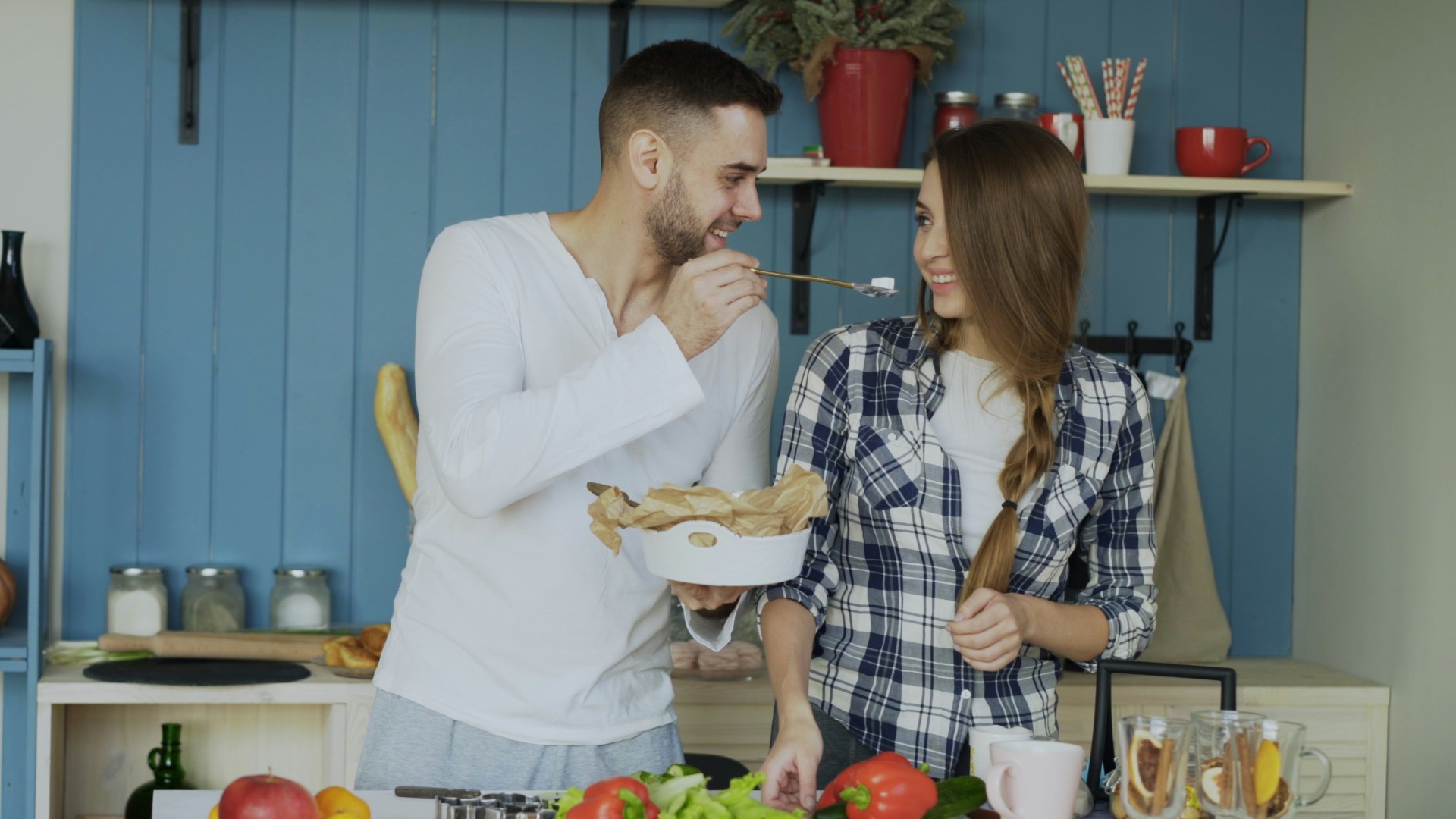 Couple cooking together in a blue kitchen.