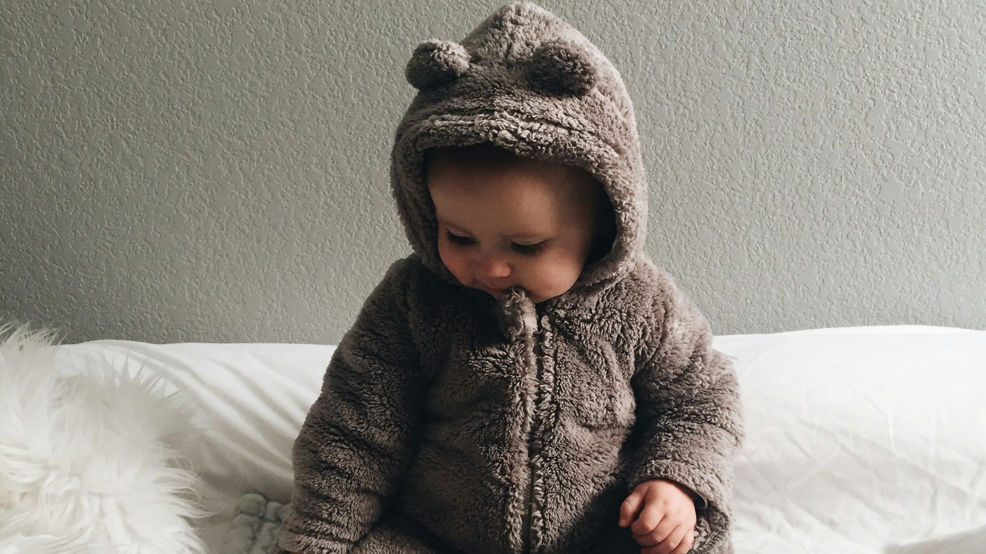 baby seating on white textile