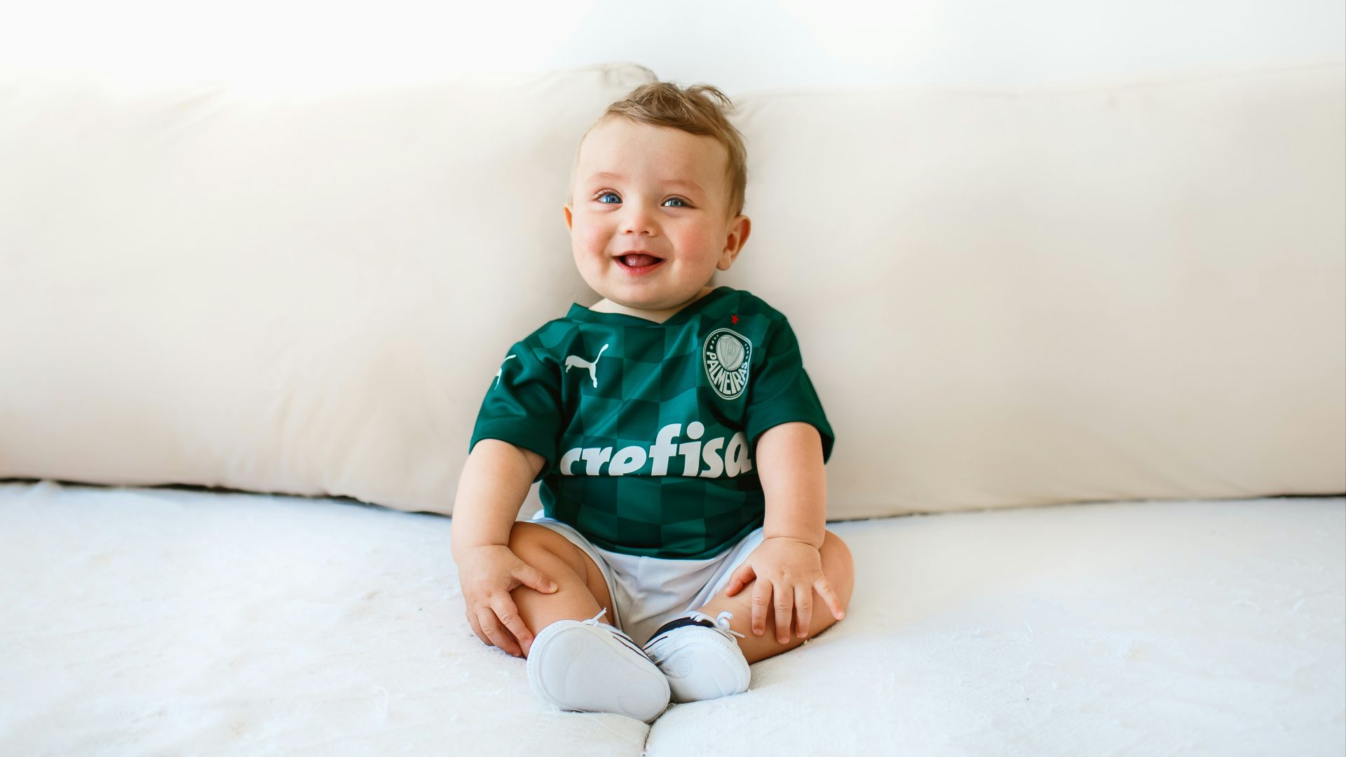 boy in green and white crew neck t-shirt sitting on white bed