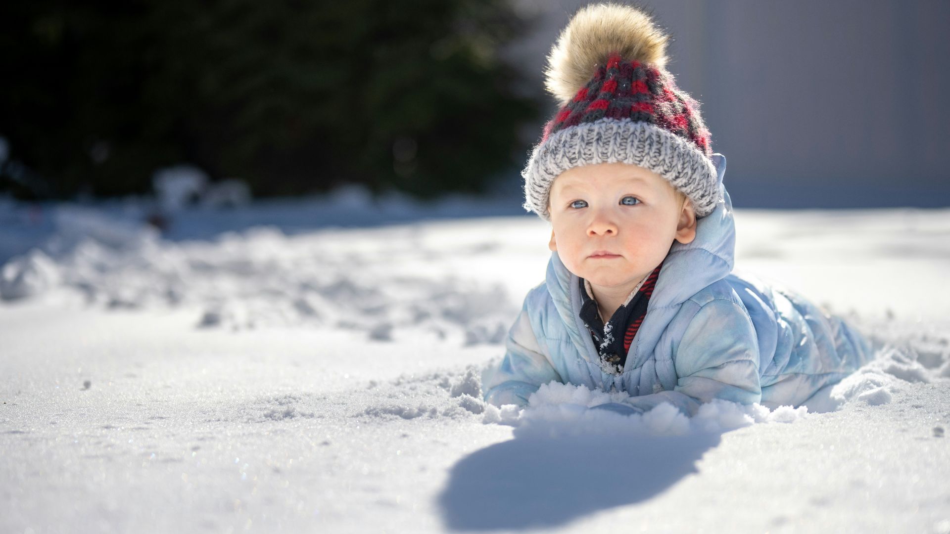 a small child laying in the snow wearing a hat