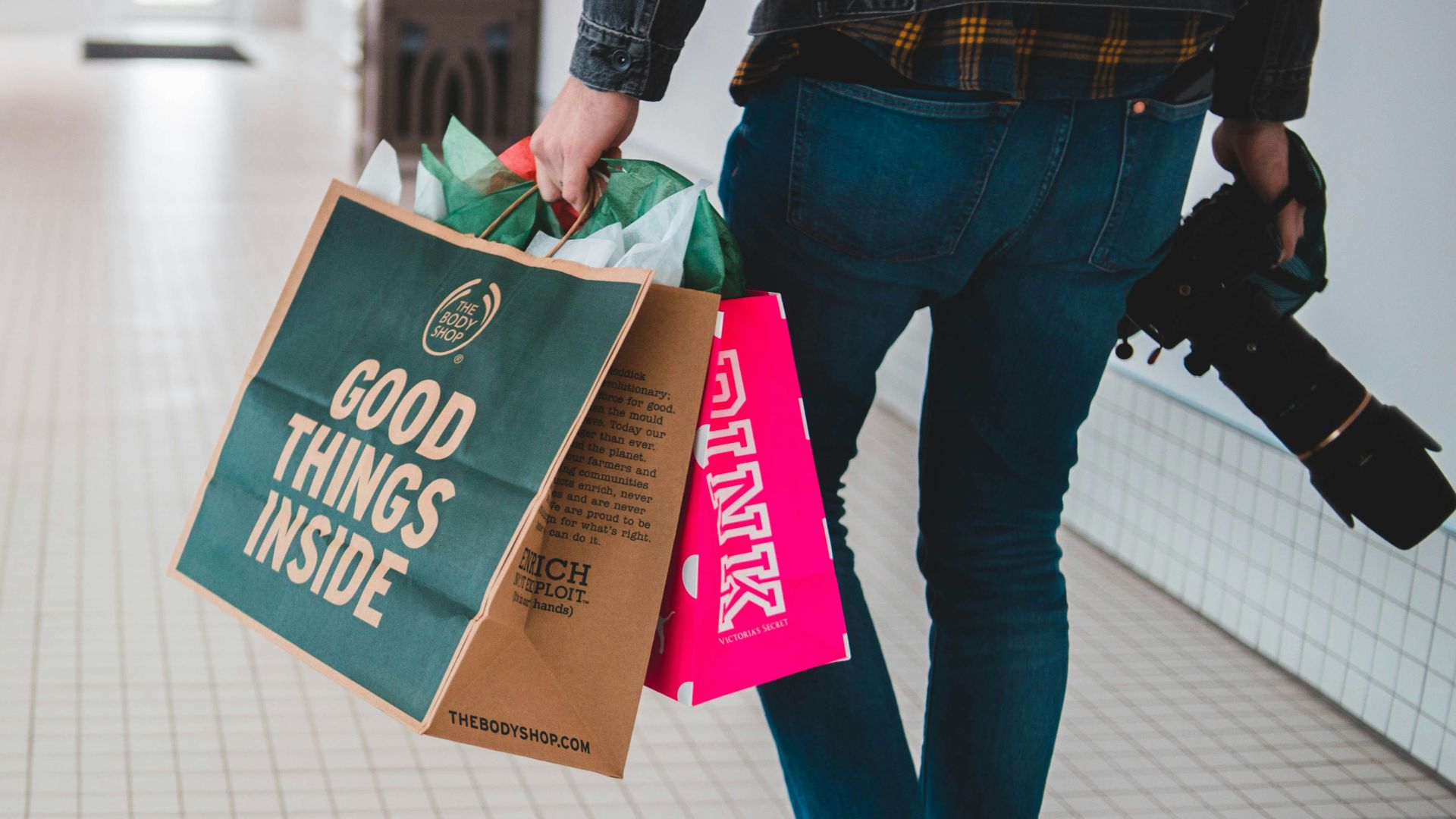 person walking while carrying a camera and paper bags