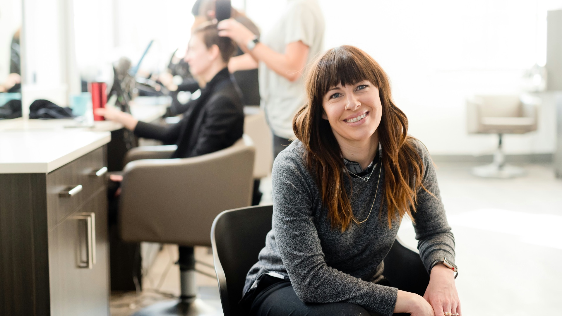woman in gray long sleeve shirt and black pants sitting on black chair