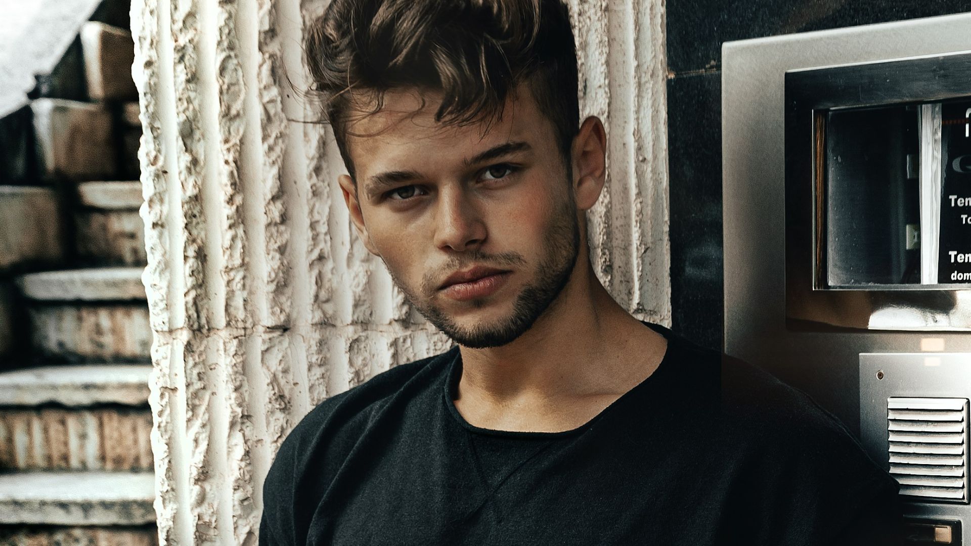 man in black crew neck long sleeve shirt standing beside gray metal cabinet