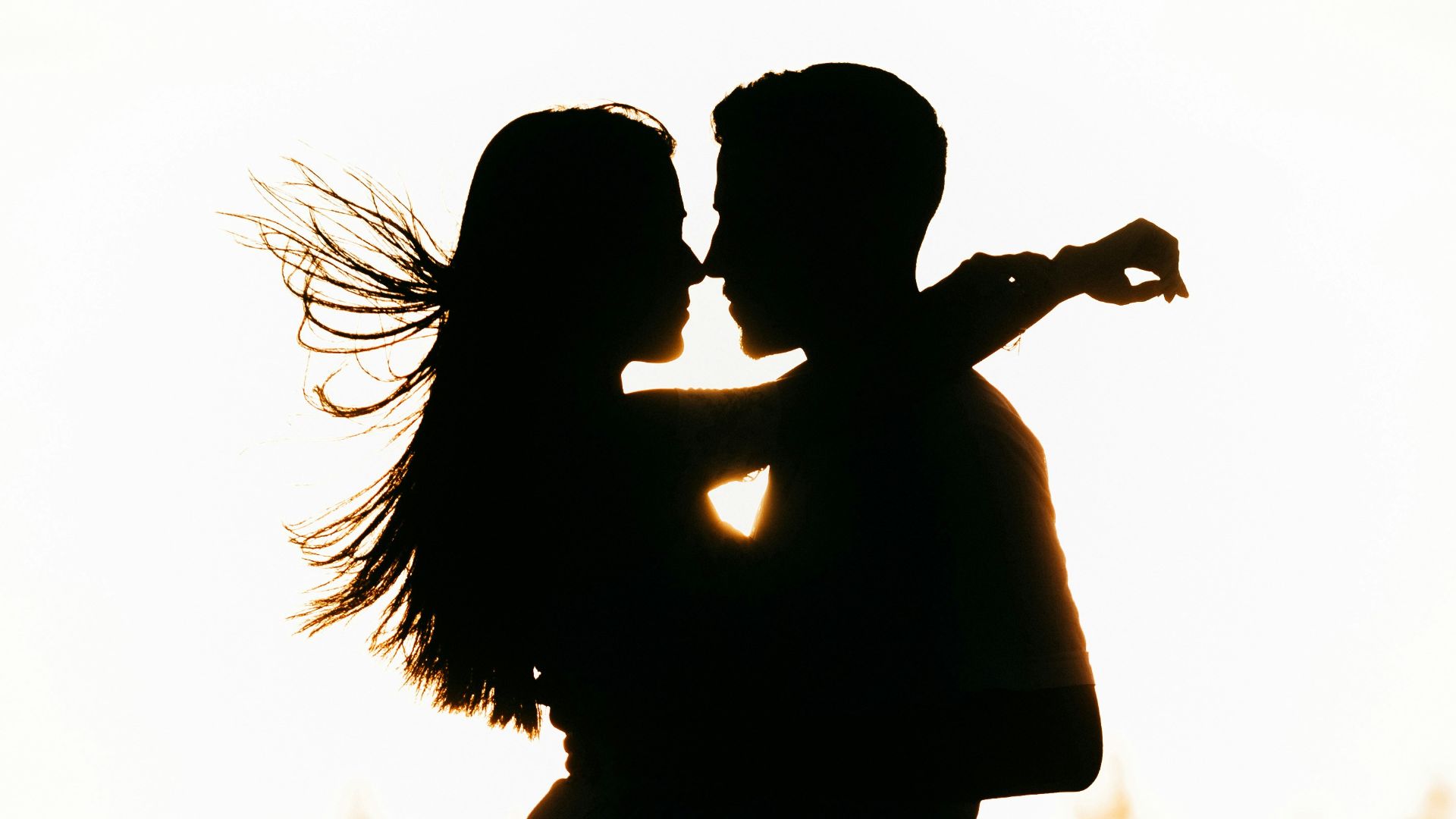 silhouette of woman standing on beach during sunset