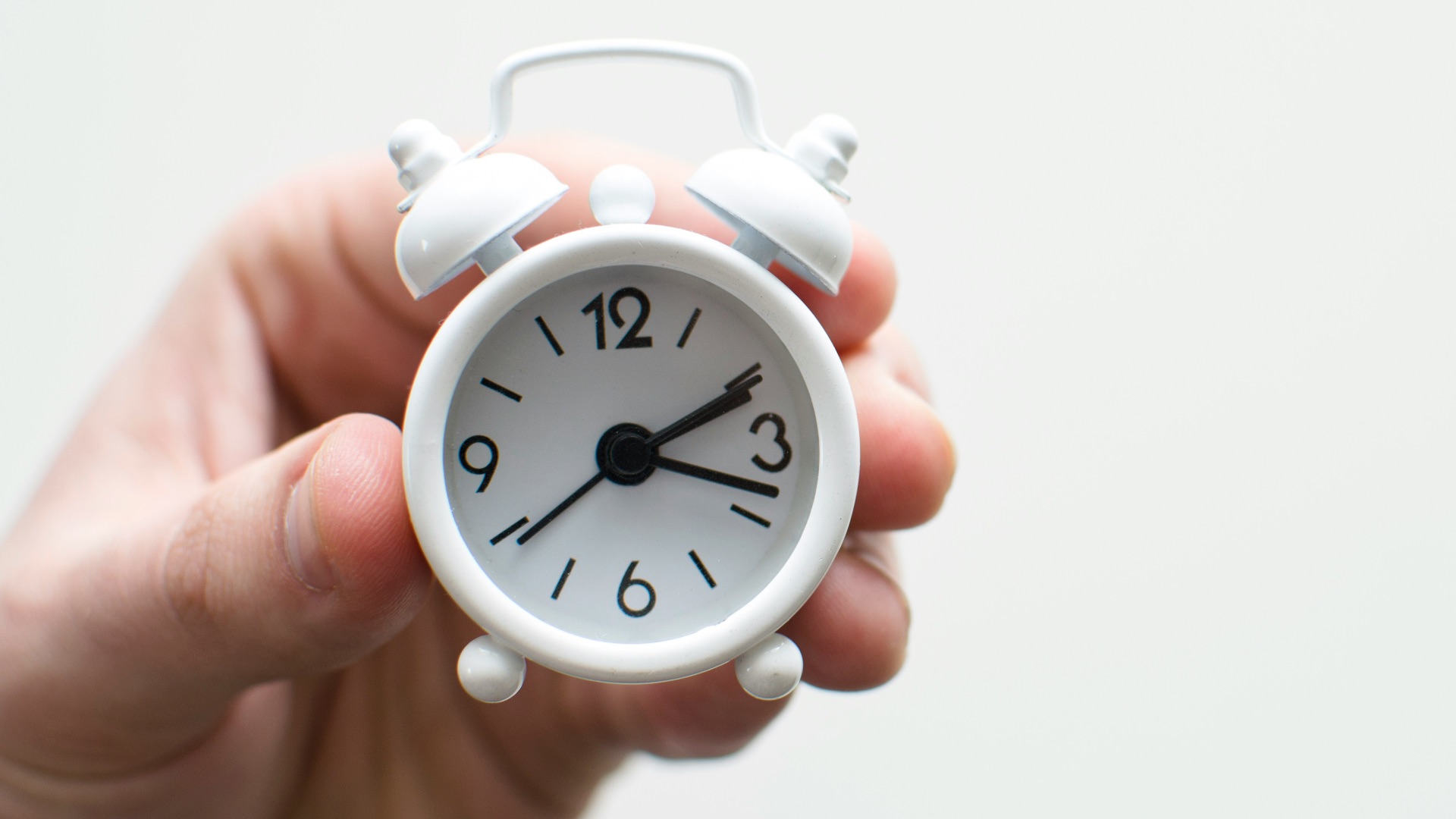 person holding white mini bell alarmclock
