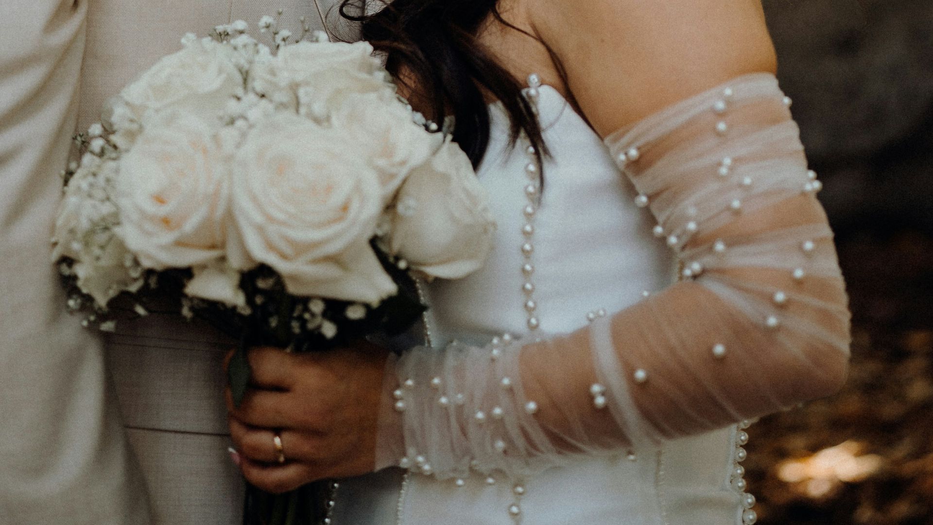 A bride and groom embrace under a large tree.