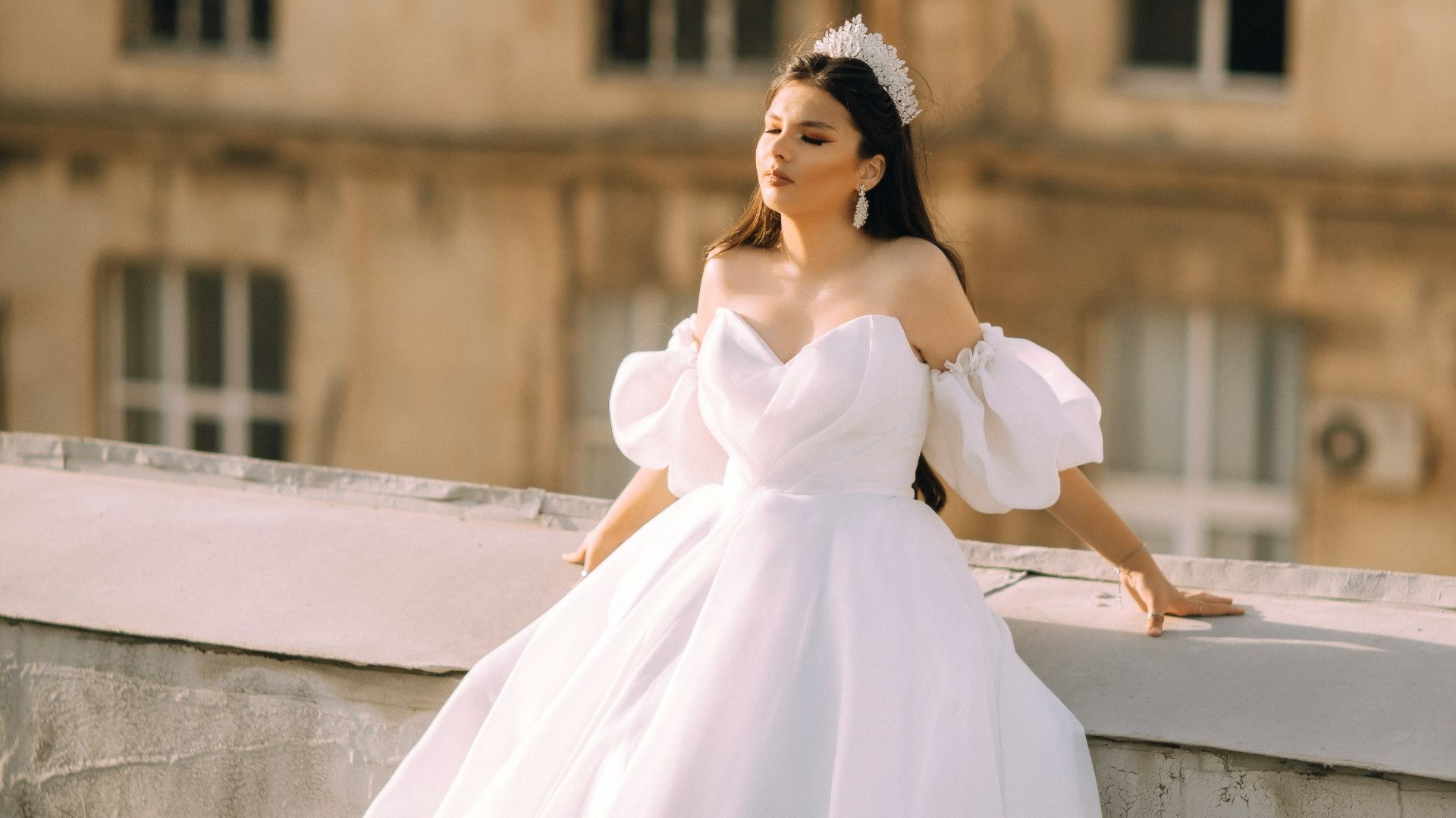 a woman in a white dress leaning on a wall