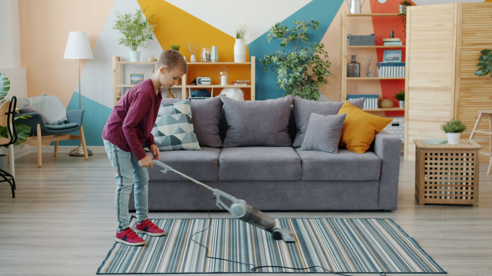 Young girl vacuuming a striped rug in a living room.