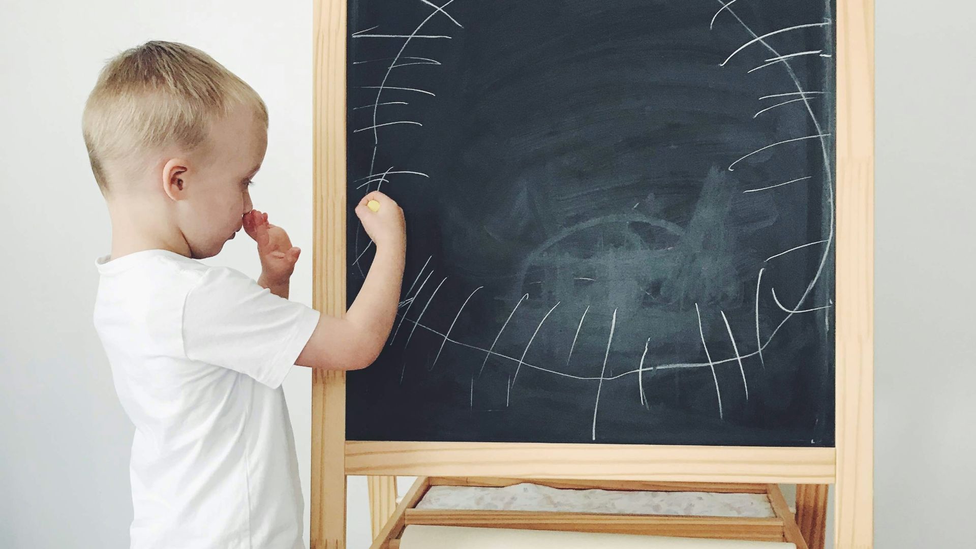 boy in white shirt standing beside black and brown wooden framed black and white map