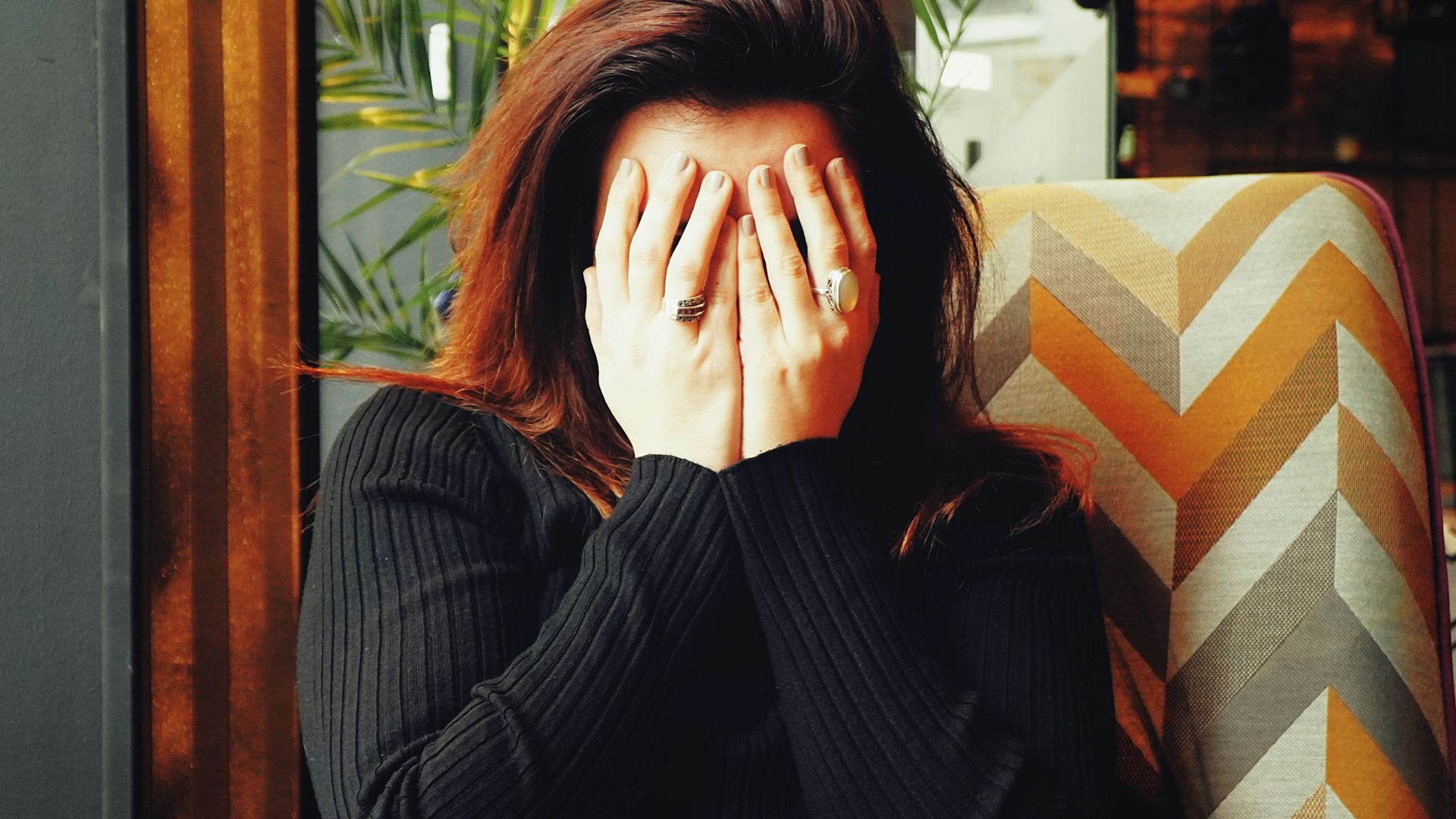 woman in black long sleeve shirt covering her face