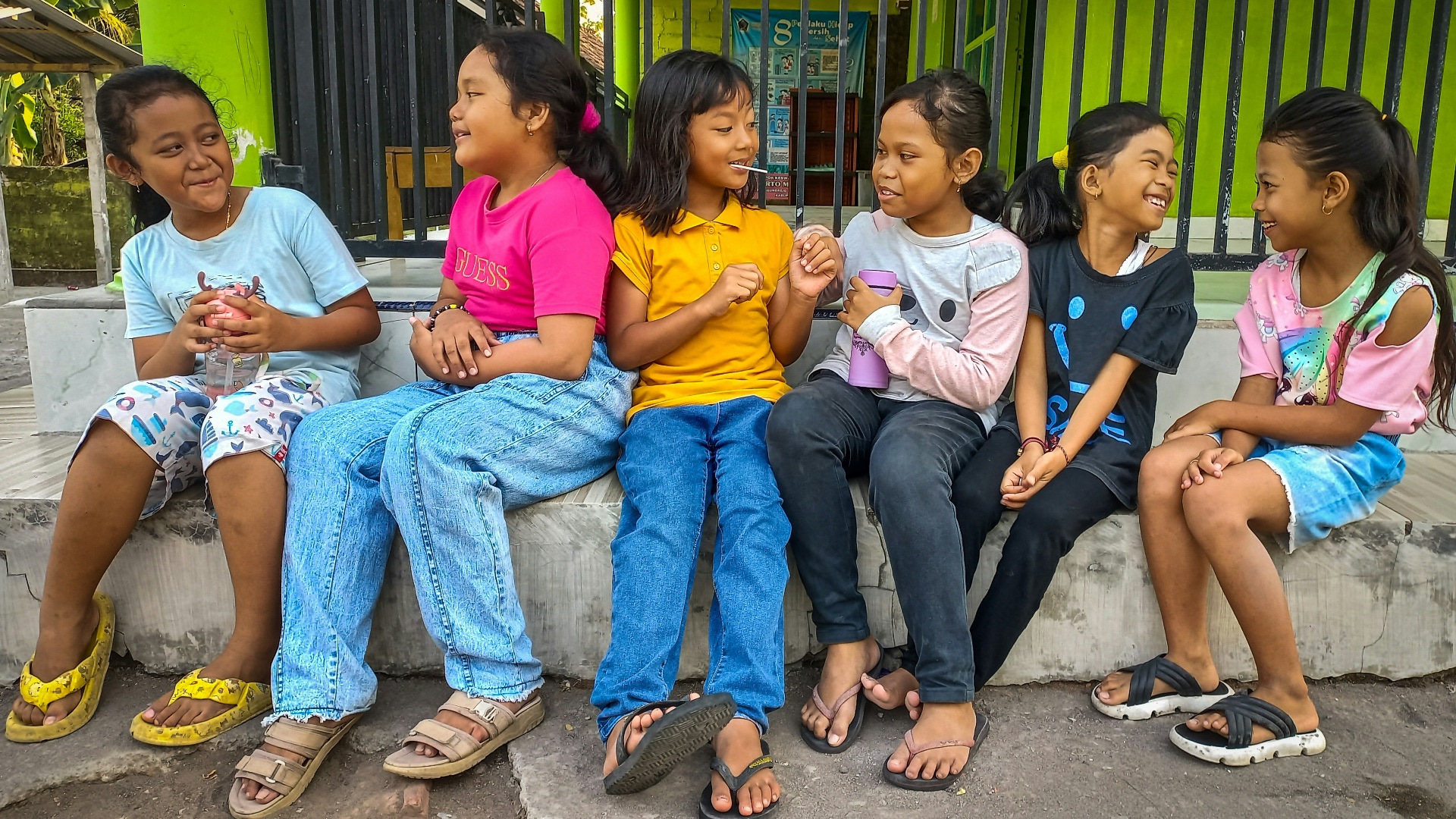 a group of young children sitting on a cement bench