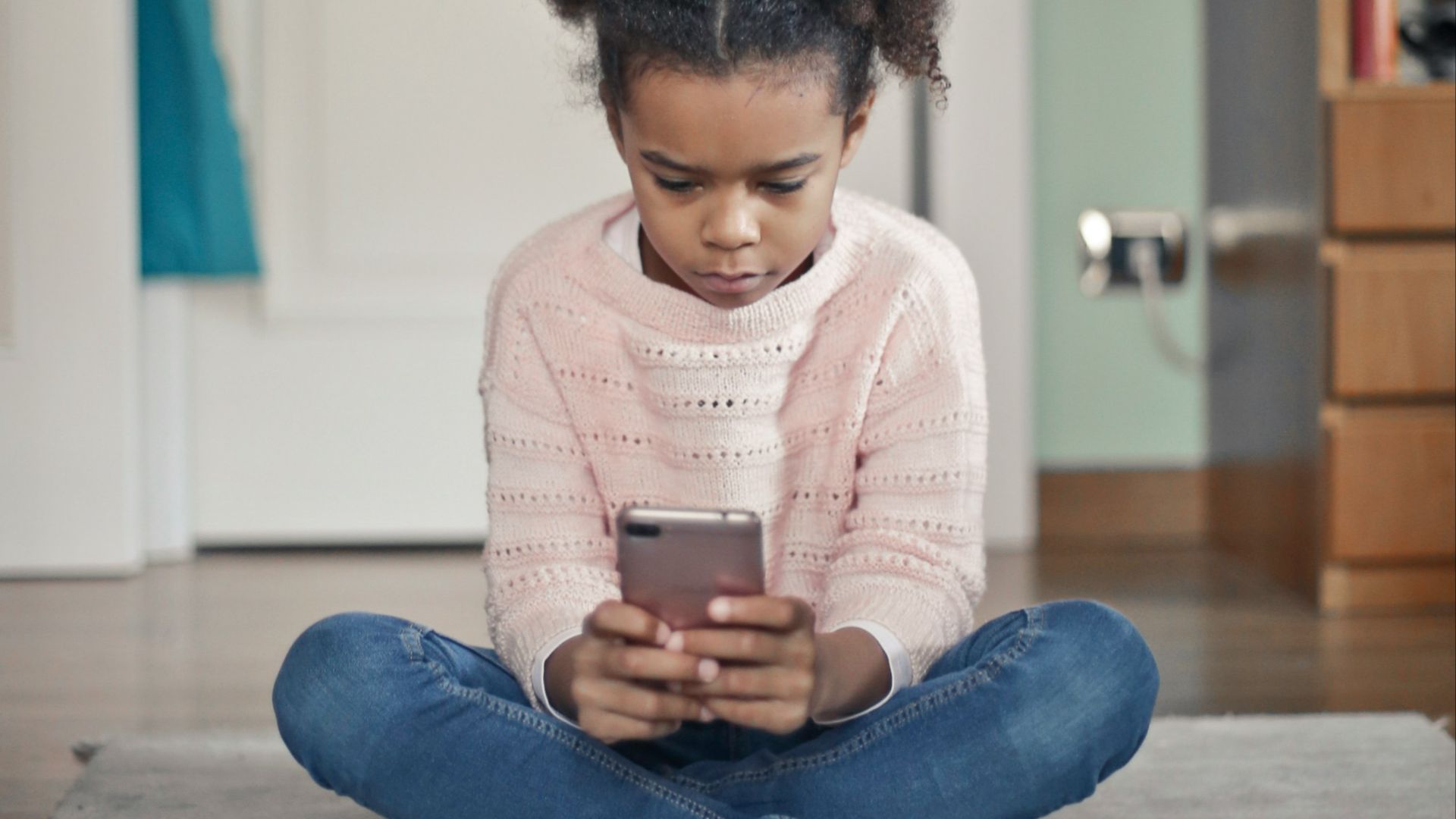 girl in white sweater and blue denim jeans sitting on floor