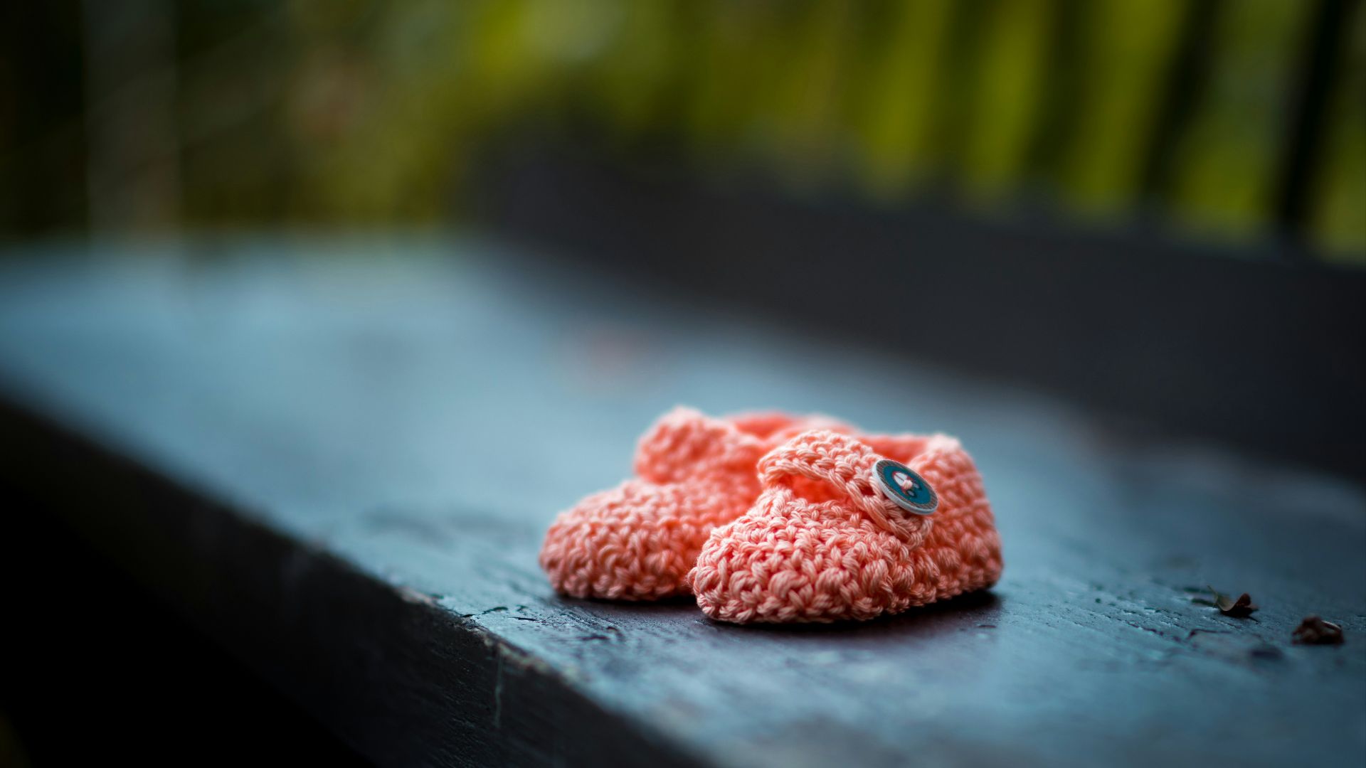 pair of baby's pink knit shoes on bench