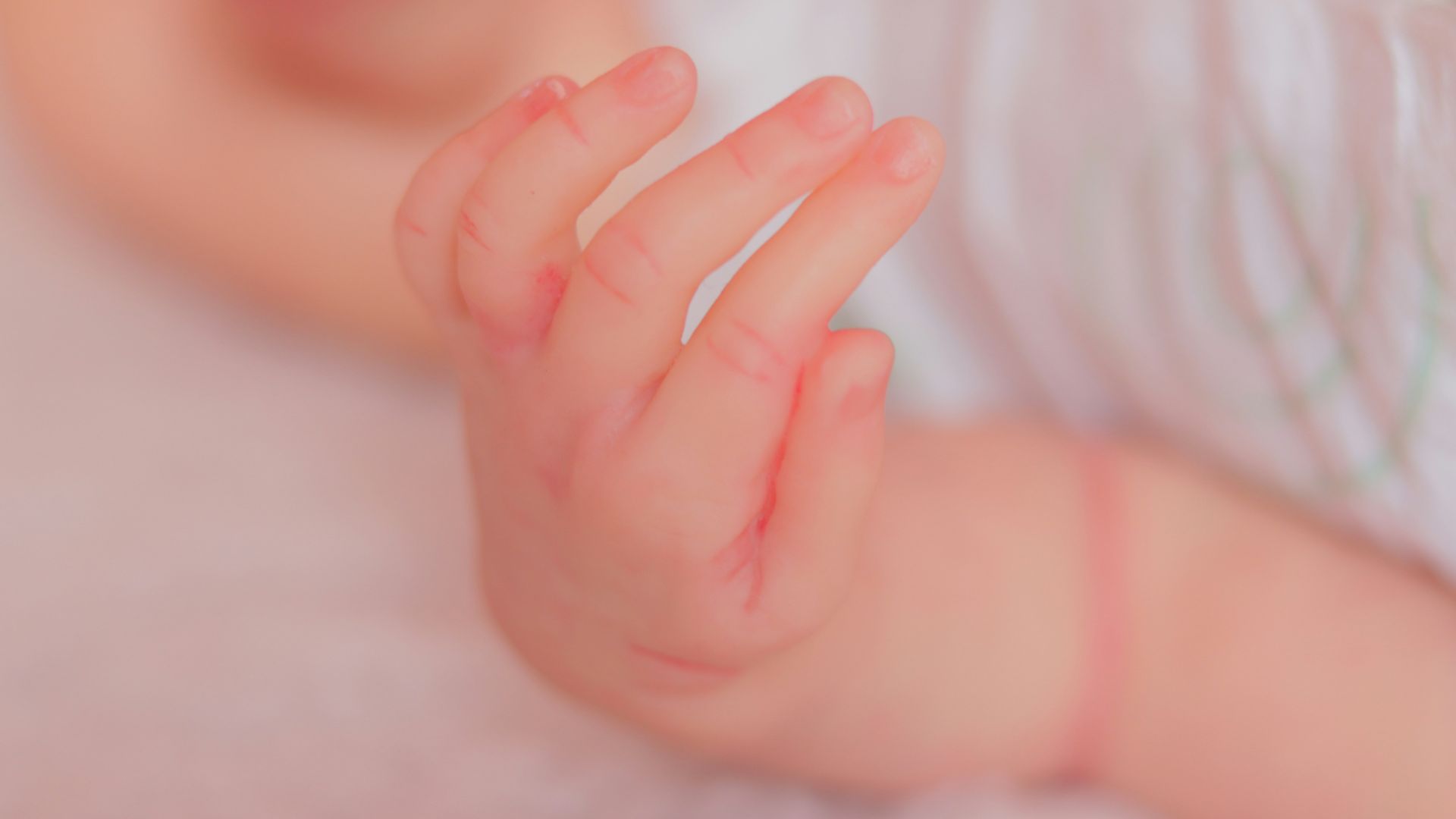 a close up of a baby's hand on a blanket