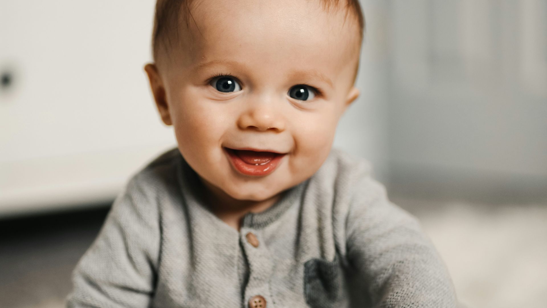 baby in gray sweater lying on white textile