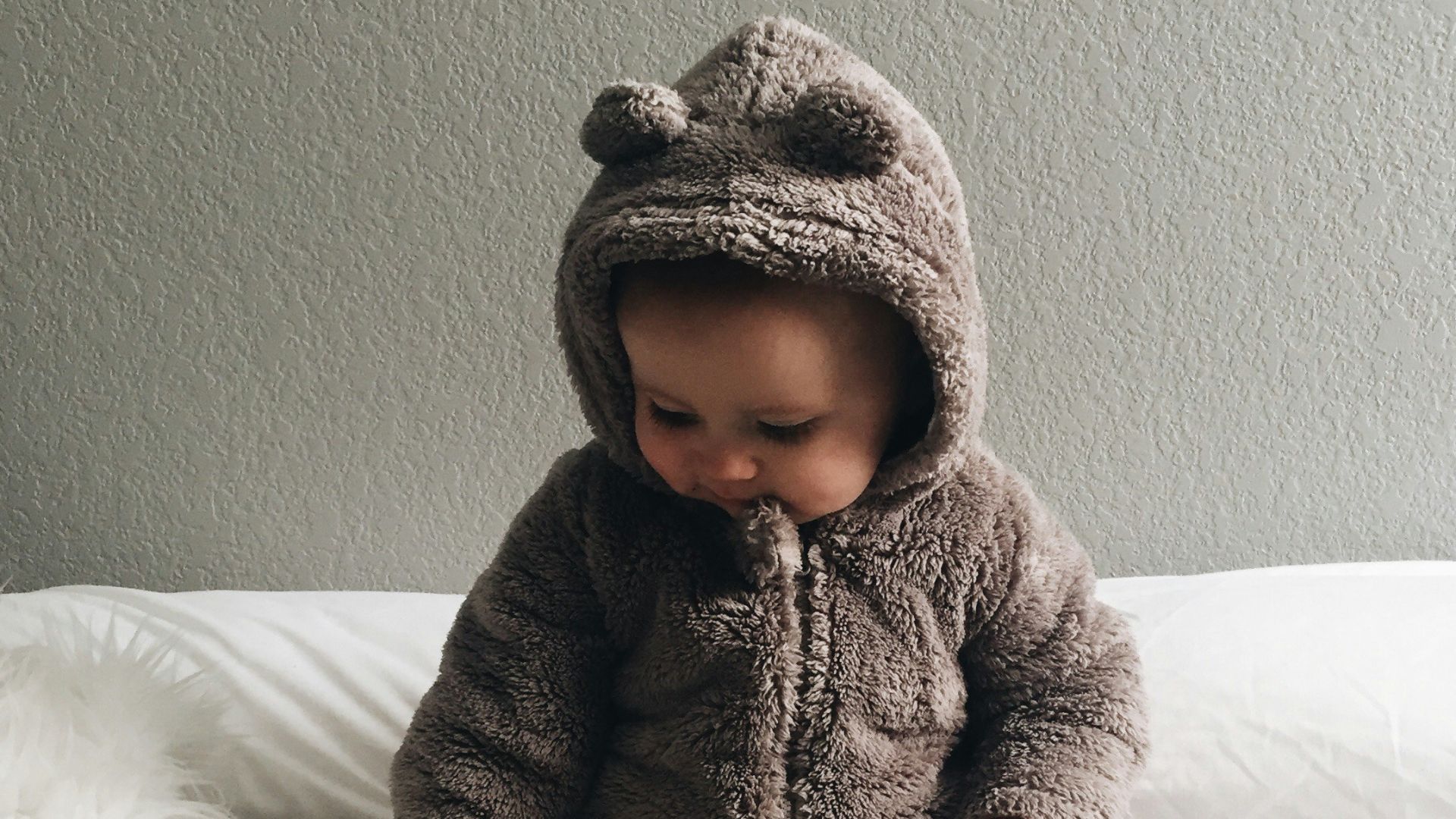 baby seating on white textile