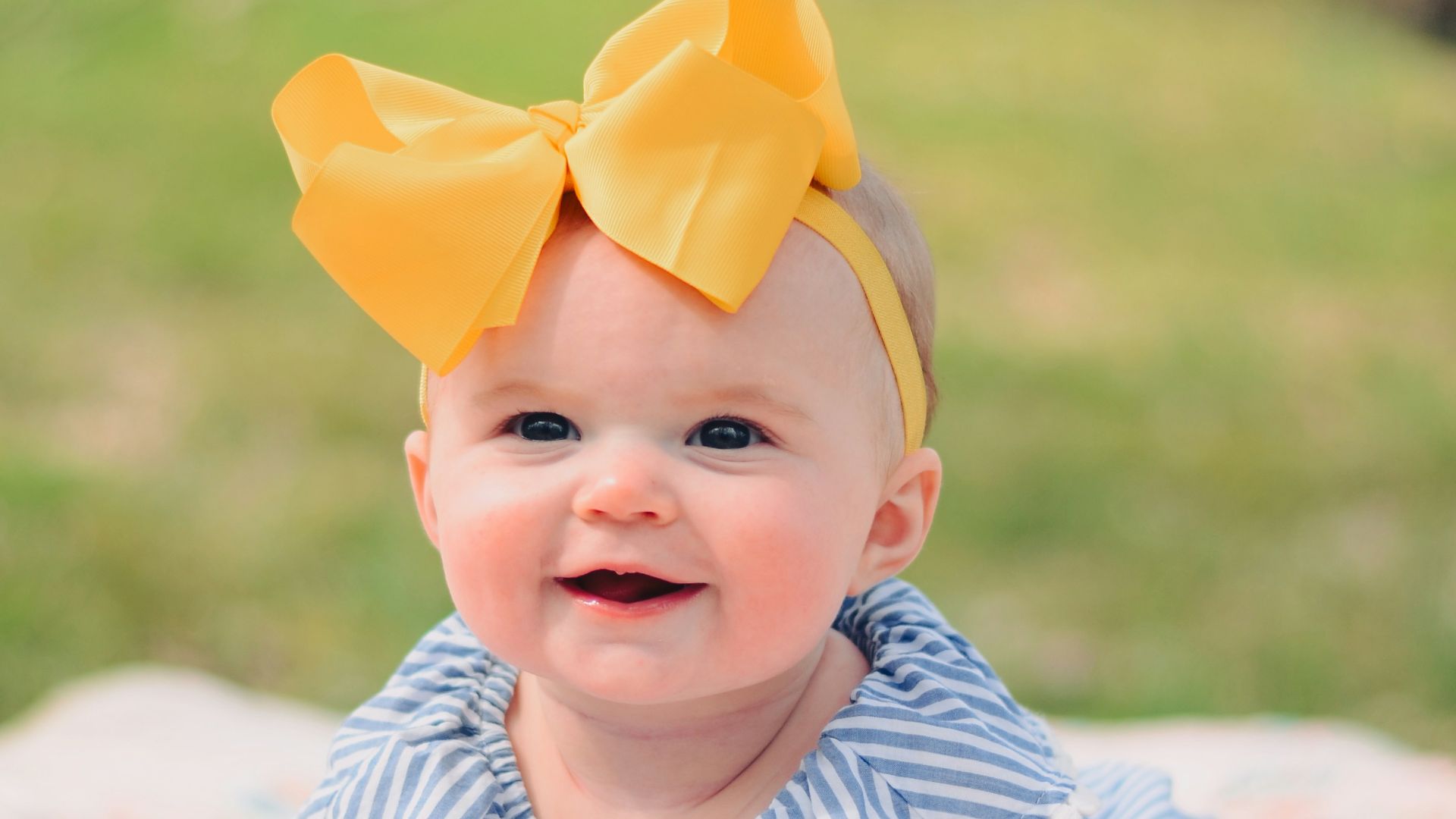 smiling baby lying forward on pink textile