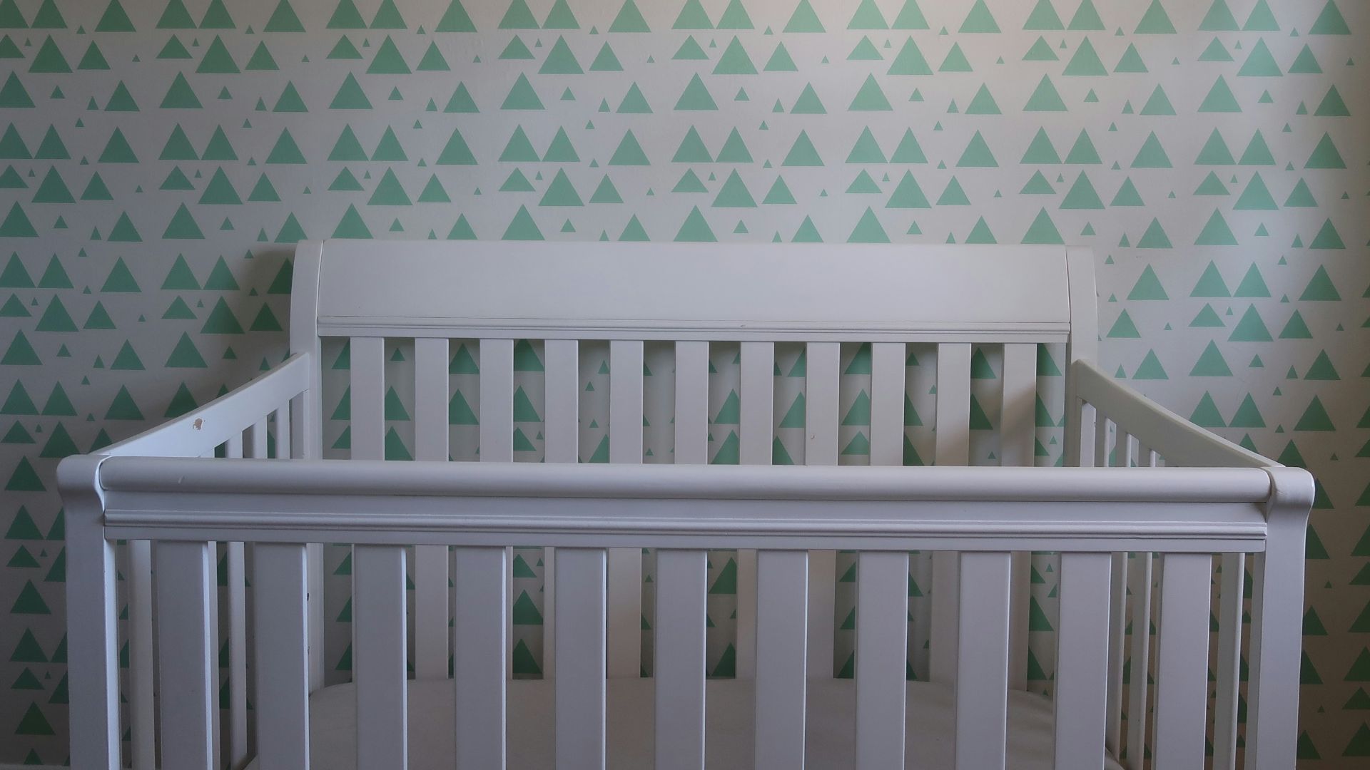 white wooden crib with white and blue polka dot wall
