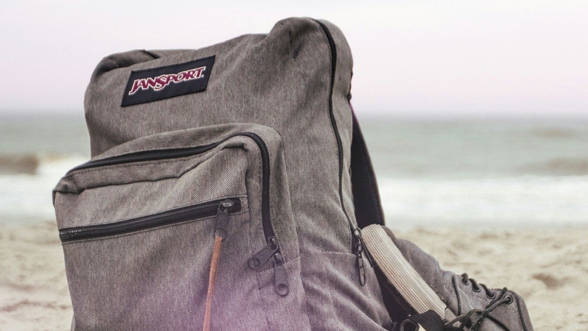black and red nike backpack on brown sand near body of water during daytime