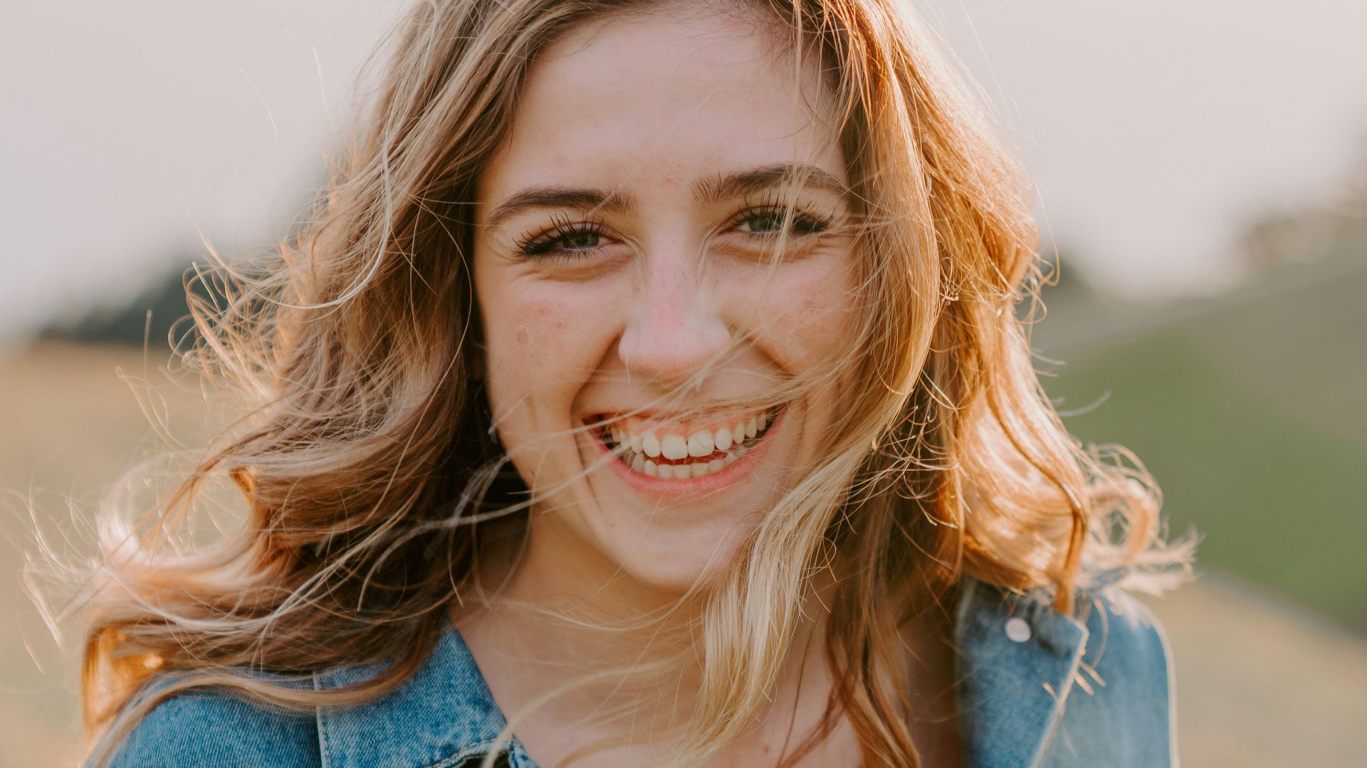 smiling woman sitting on grass during daytime