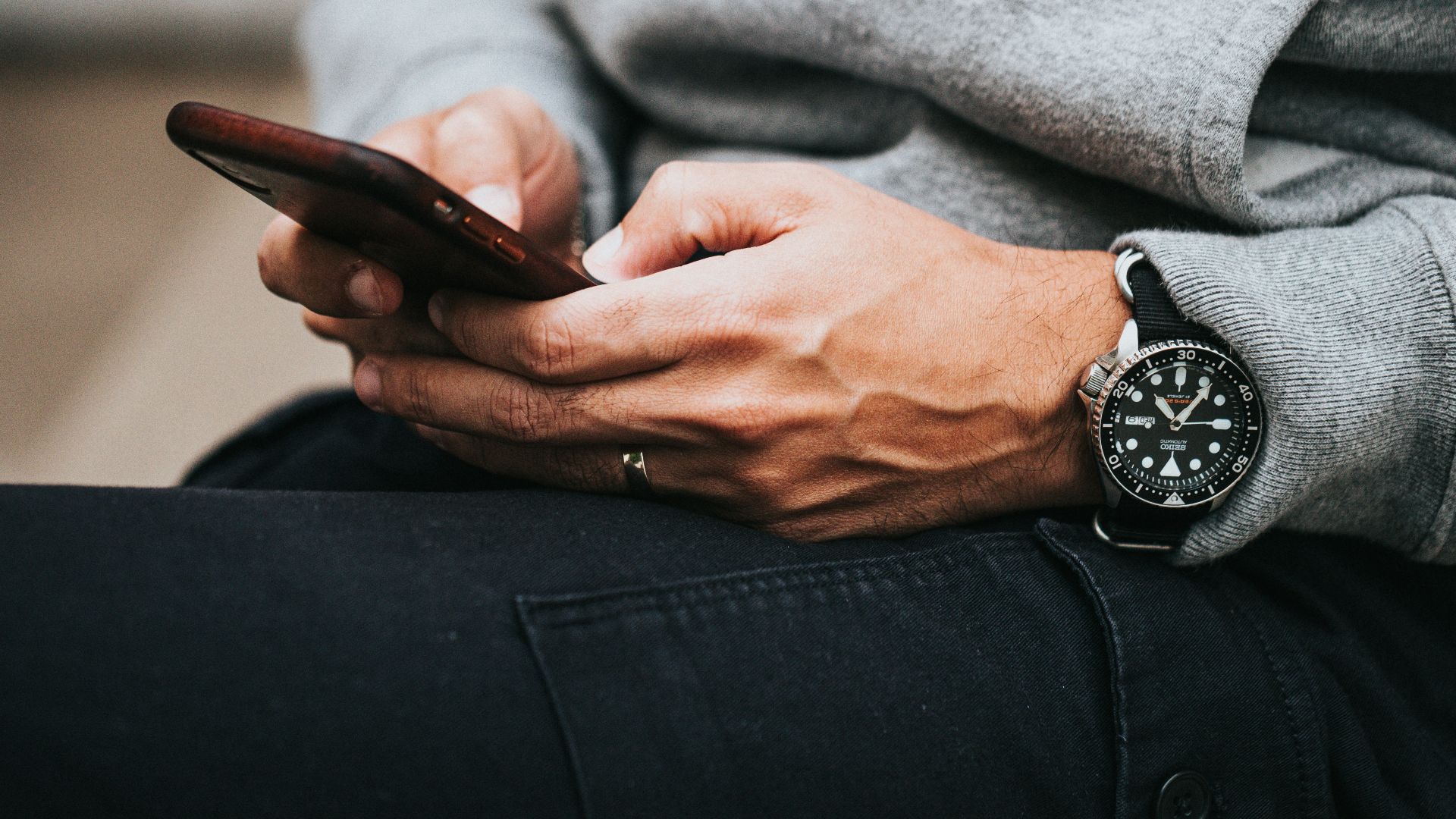 person in gray sweater wearing black and silver chronograph watch