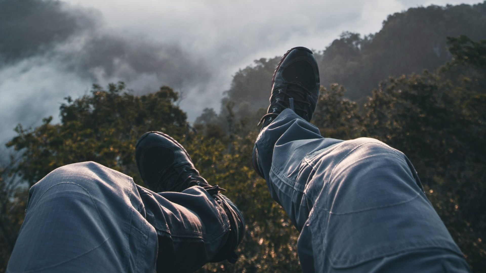 person's feet facing foggy mountain field during golden hour