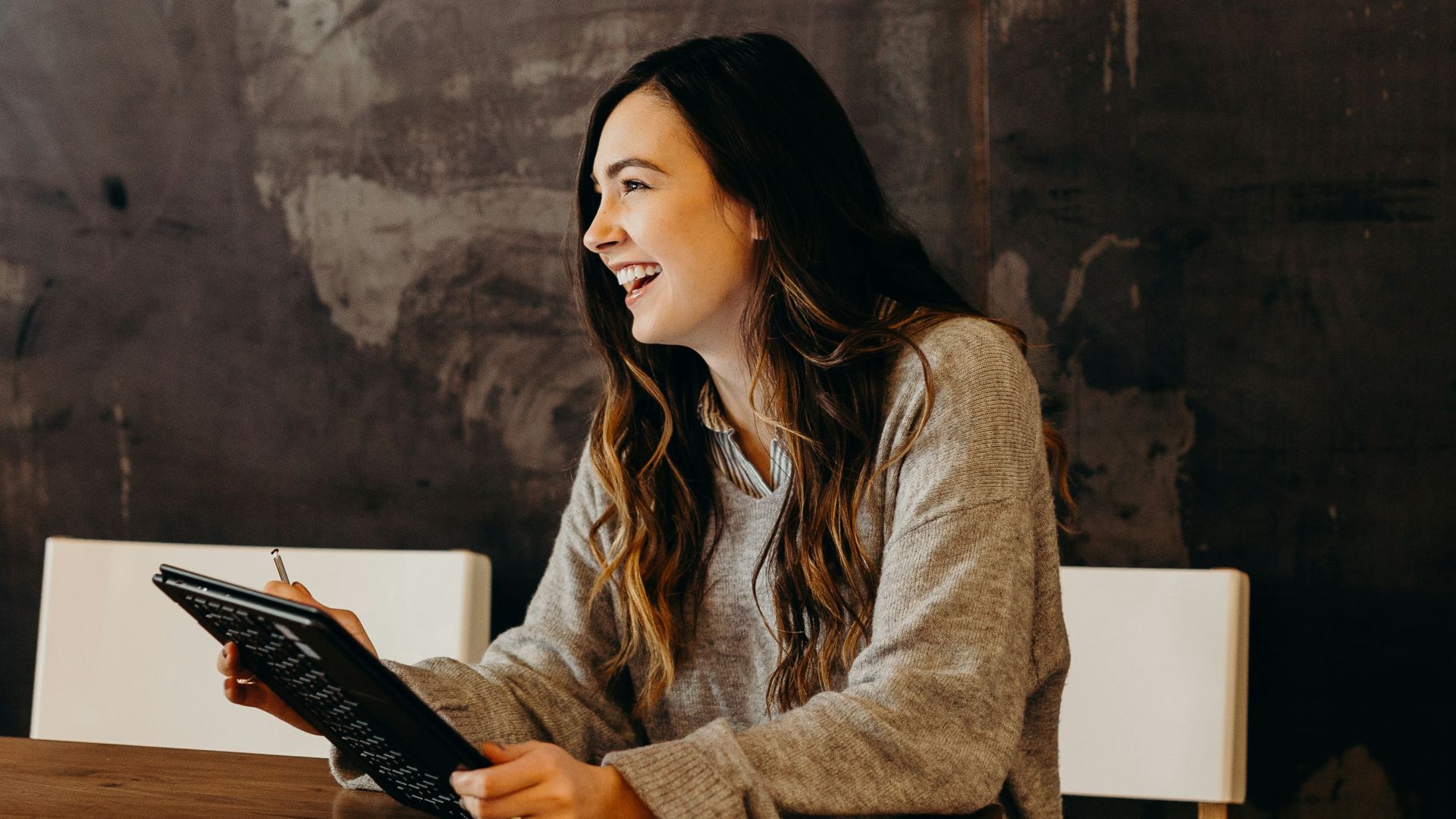 woman sitting around table holding tablet