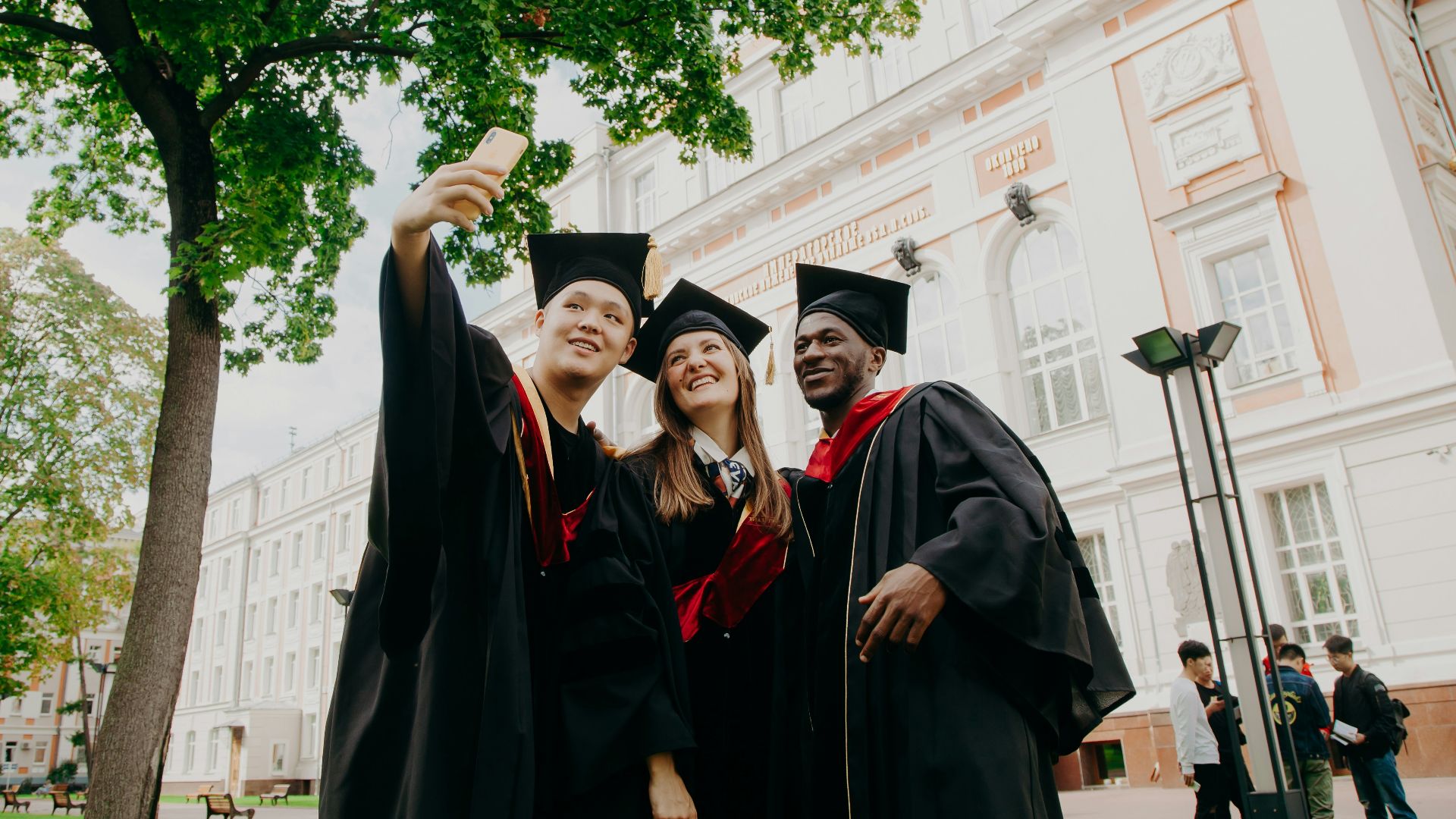 3 women in black academic dress standing near green tree during daytime