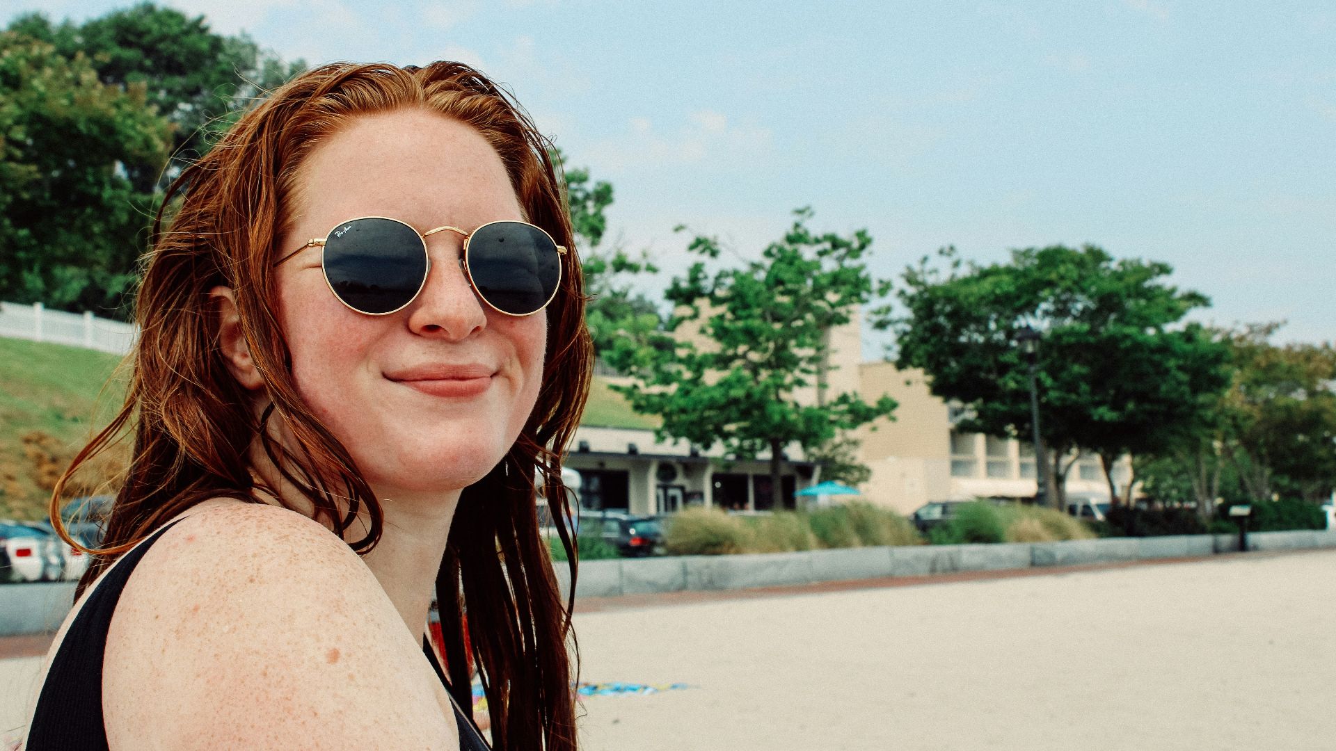 a woman wearing sunglasses sitting on a beach