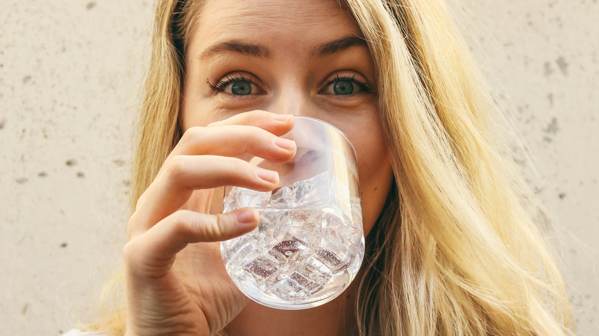 woman in white crew neck shirt drinking water