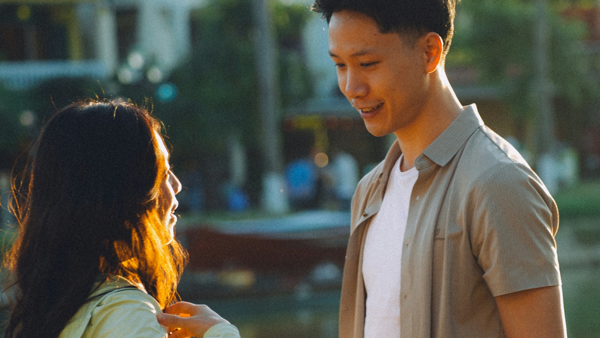 A couple talking by a calm river at sunset.