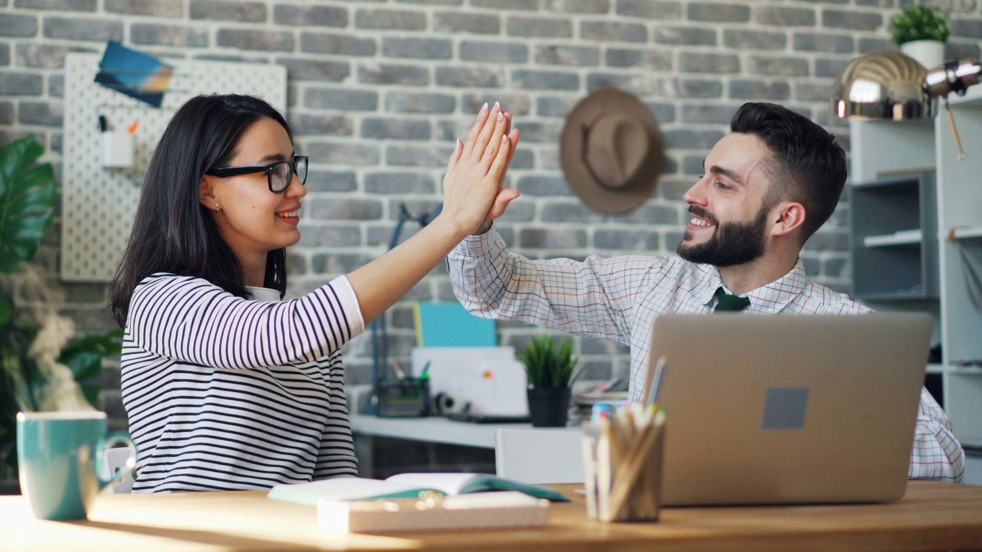 a man and a woman high fiving each other in front of a laptop