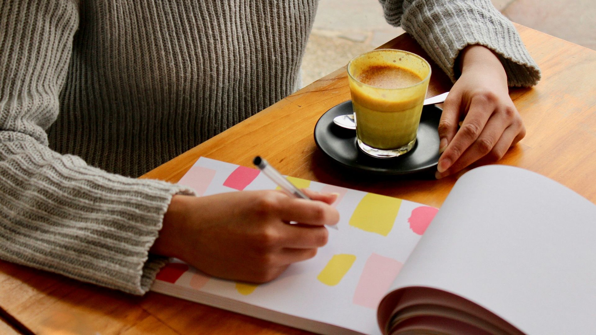 person holding pen with coffee on table