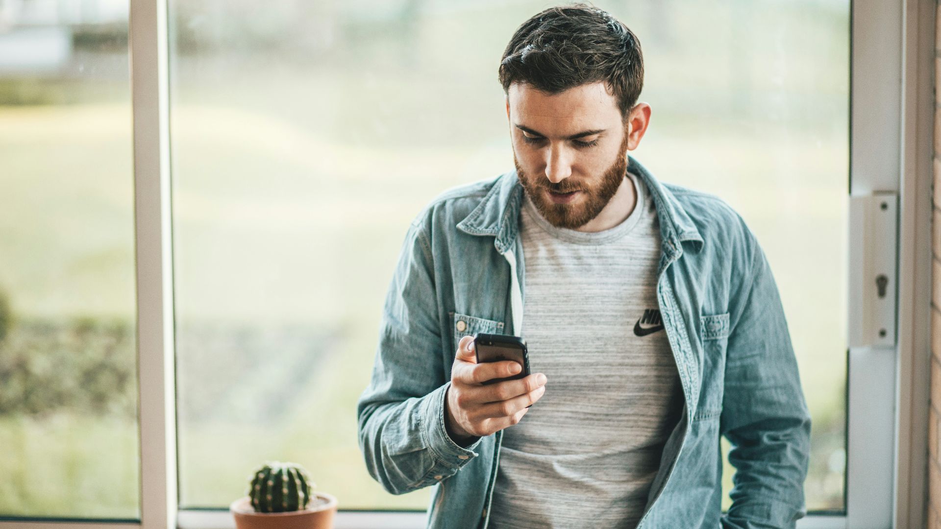 man holding a smartphone near the window