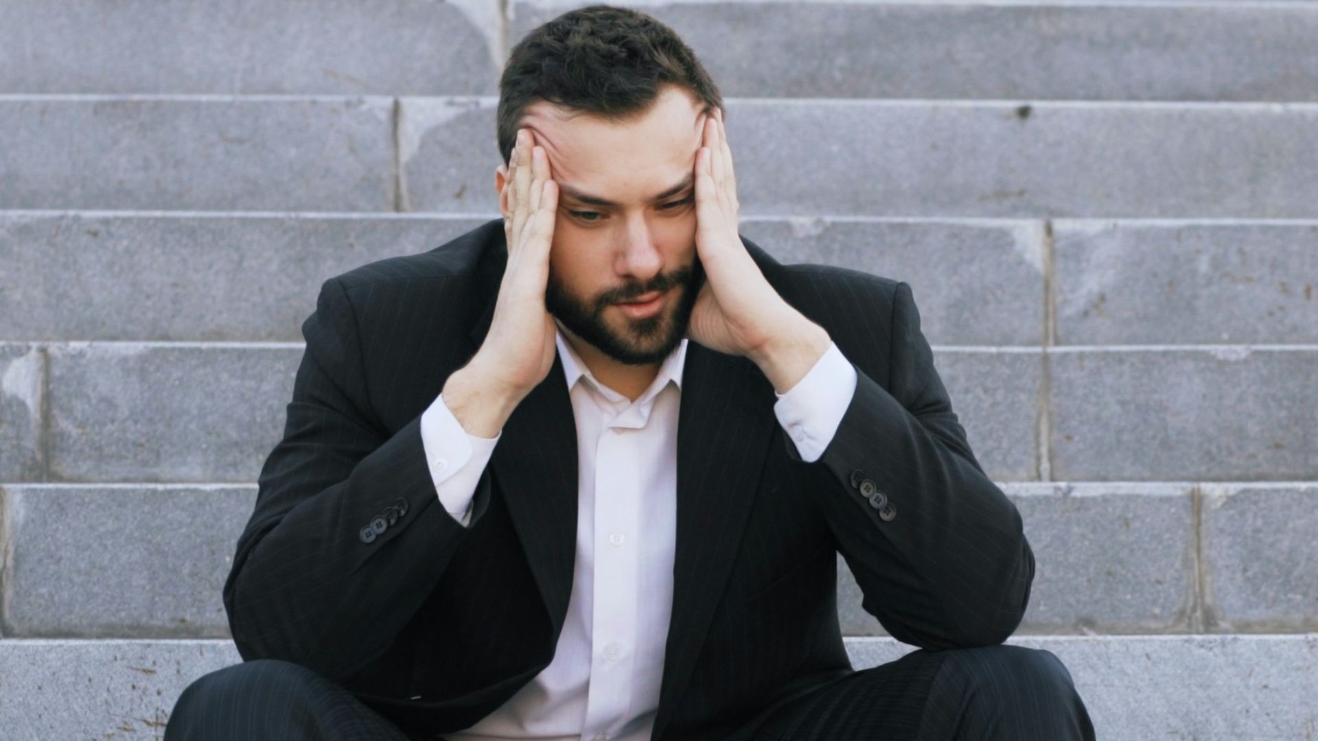 Man in suit sitting on stairs with head in hands