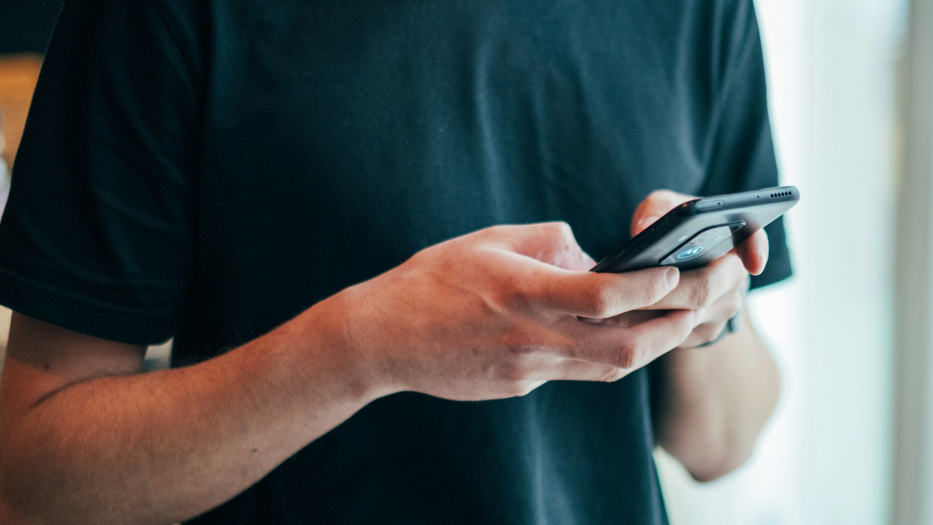 man in black crew-neck top using smartphone