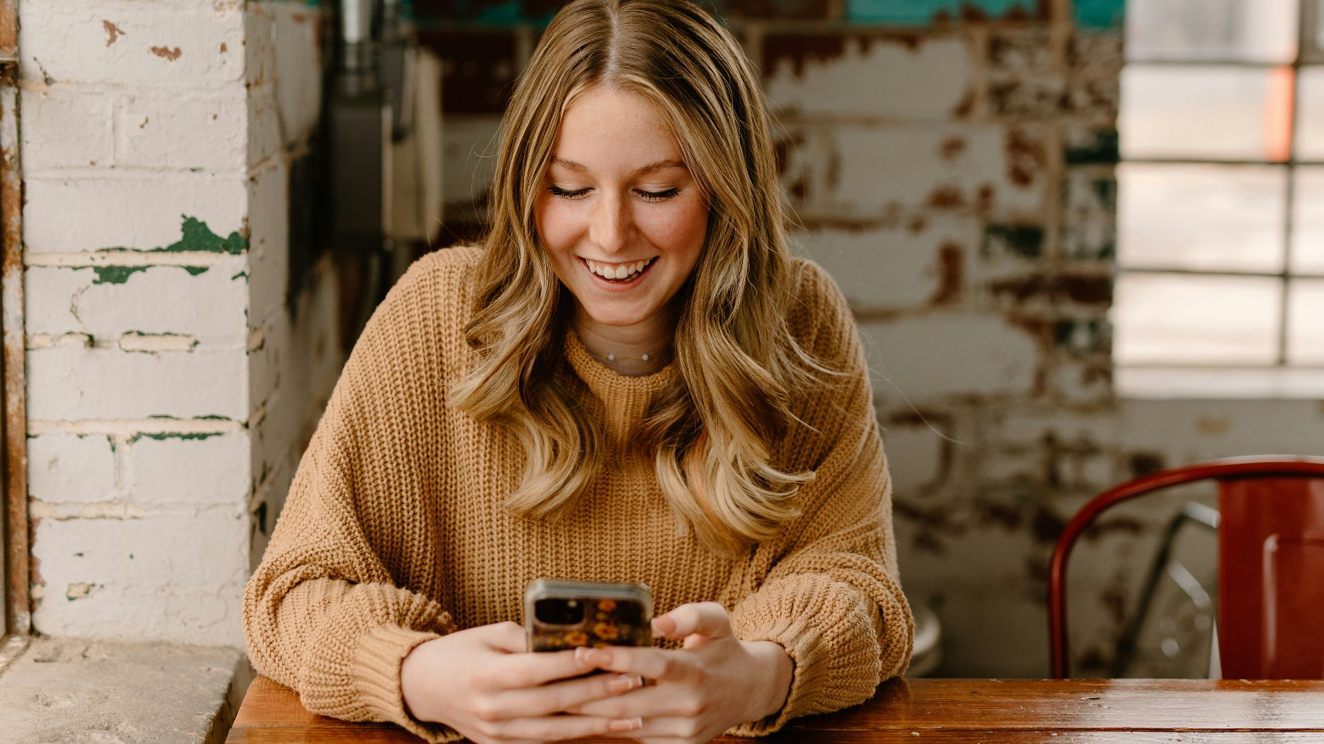 a woman sitting at a table looking at her cell phone