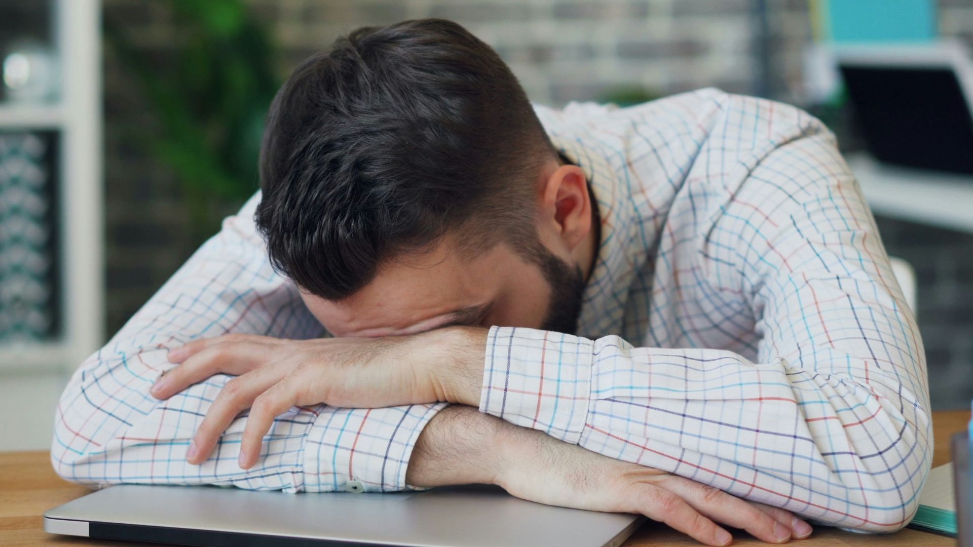 a man sitting at a desk with his head in his hands