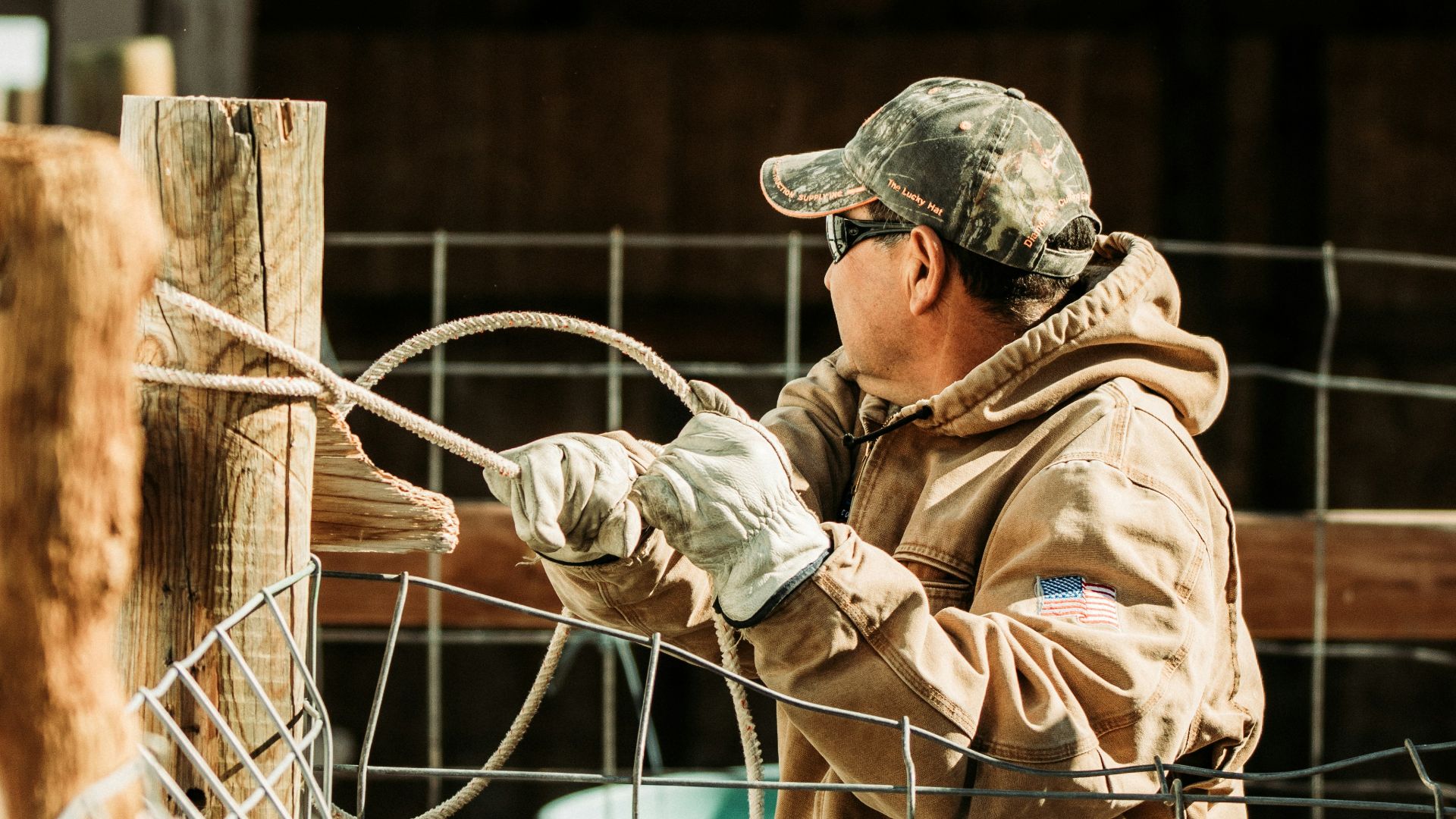 man in brown jacket and beige pants standing near gray metal fence during daytime