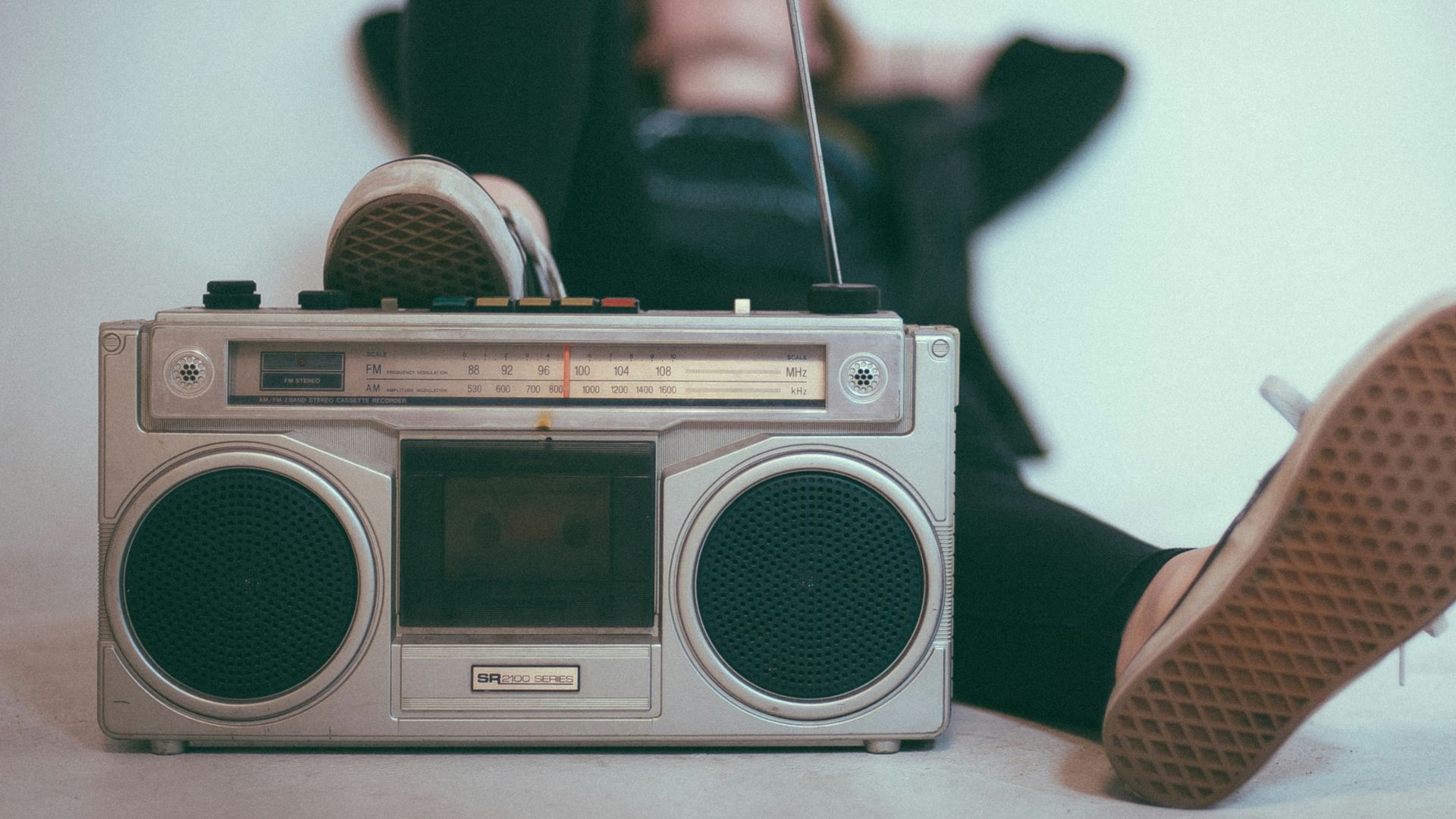 woman laying on bed near gray radio