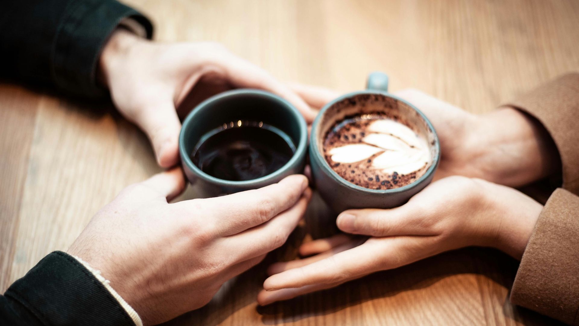 two person holding ceramic mugs with coffee