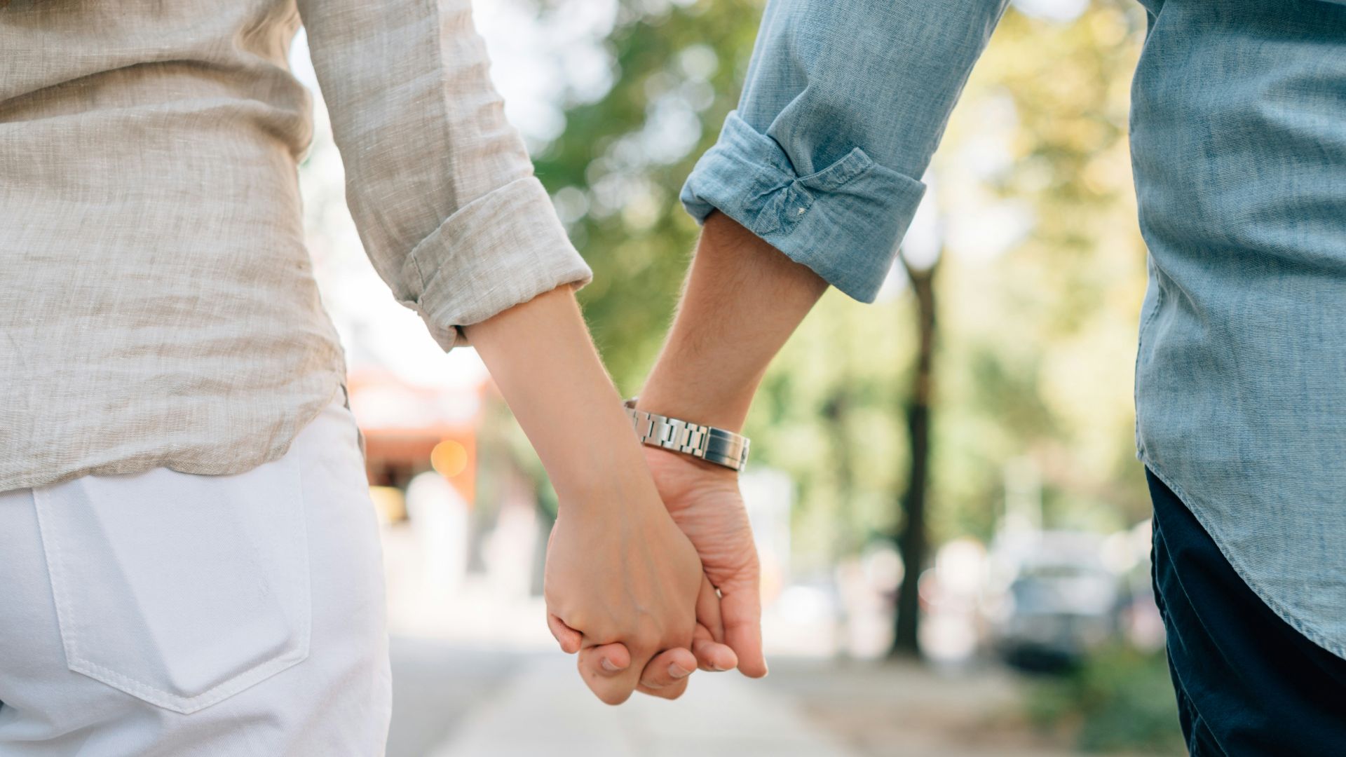 man and woman holding hands together in walkway during daytime