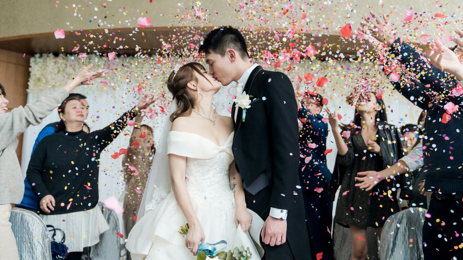 man in black suit kissing woman in white wedding dress