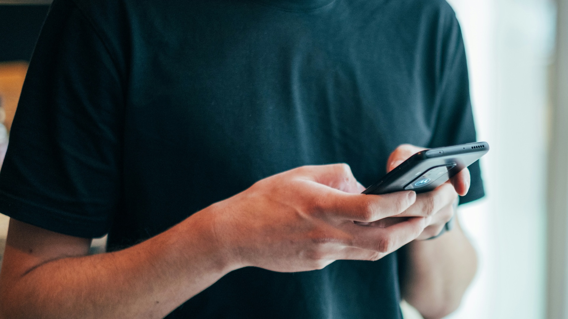 man in black crew-neck top using smartphone