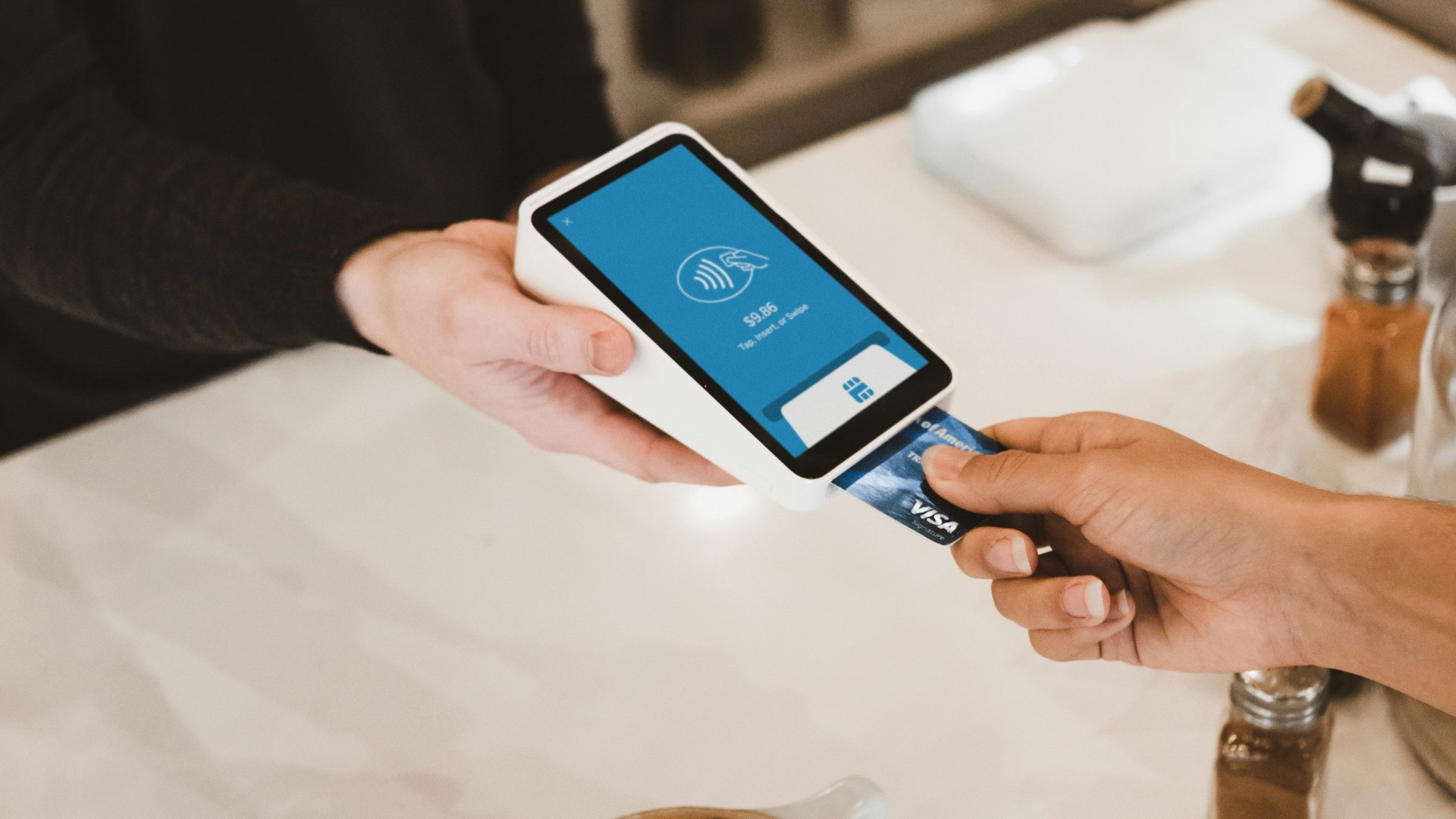 person putting magstripe card near black card terminal