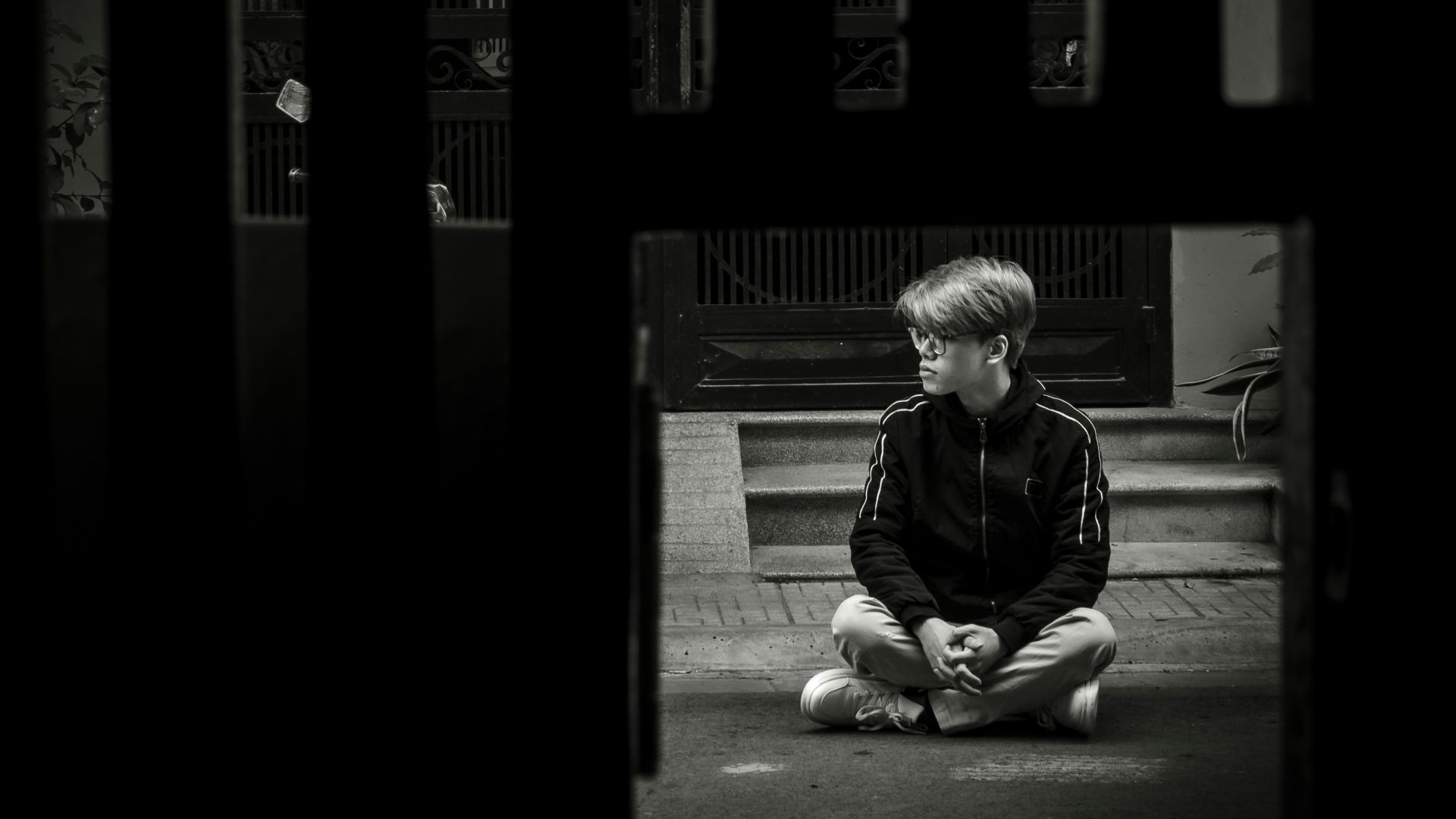 a young boy sitting on the ground in front of a door