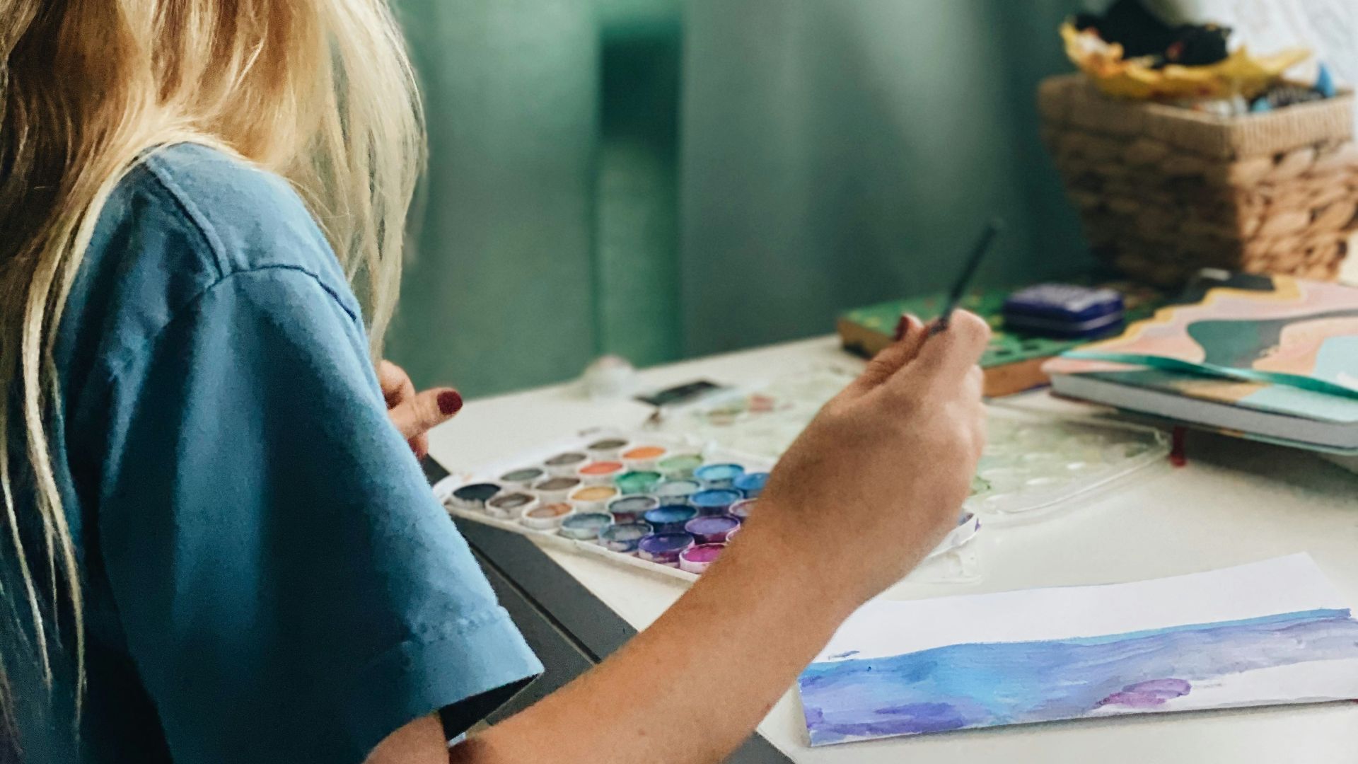 woman in blue shirt painting on white paper