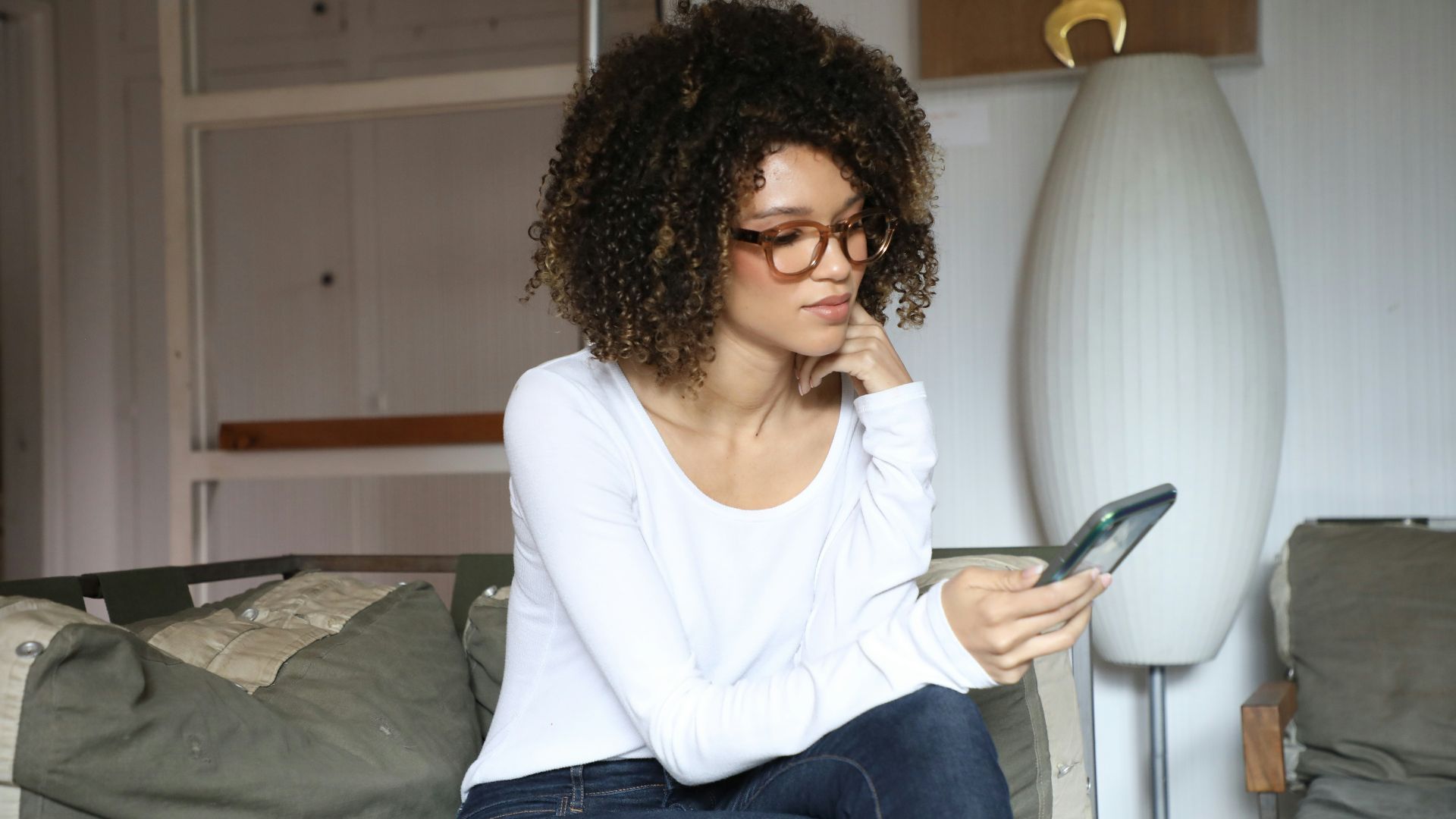 woman in white long sleeve shirt and blue denim jeans sitting on bed